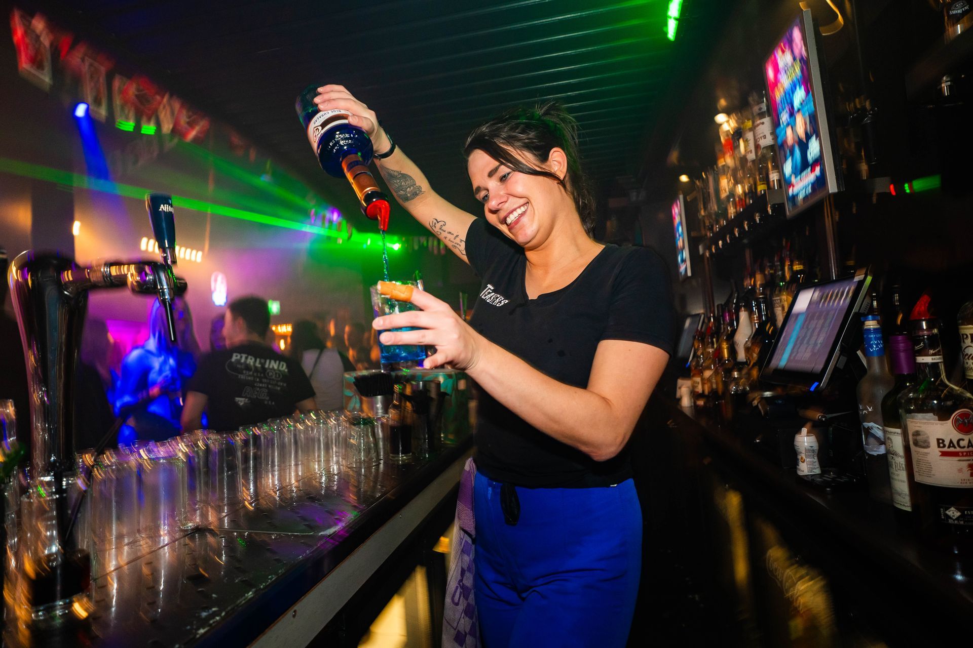 Een vrouw schenkt een drankje in een glas in een bar.