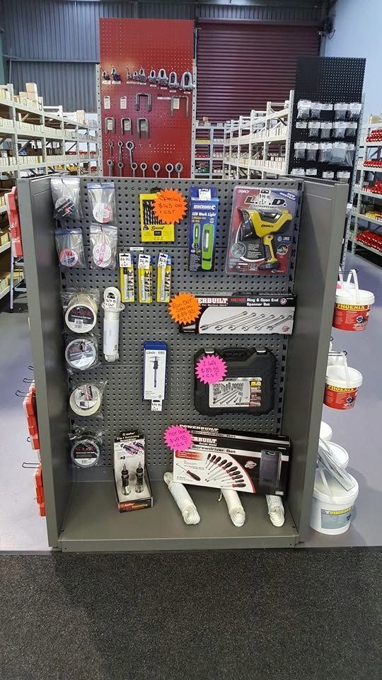 Store display rack with assorted pet accessories, toys, bowls, and grooming items on pegboard shelves.