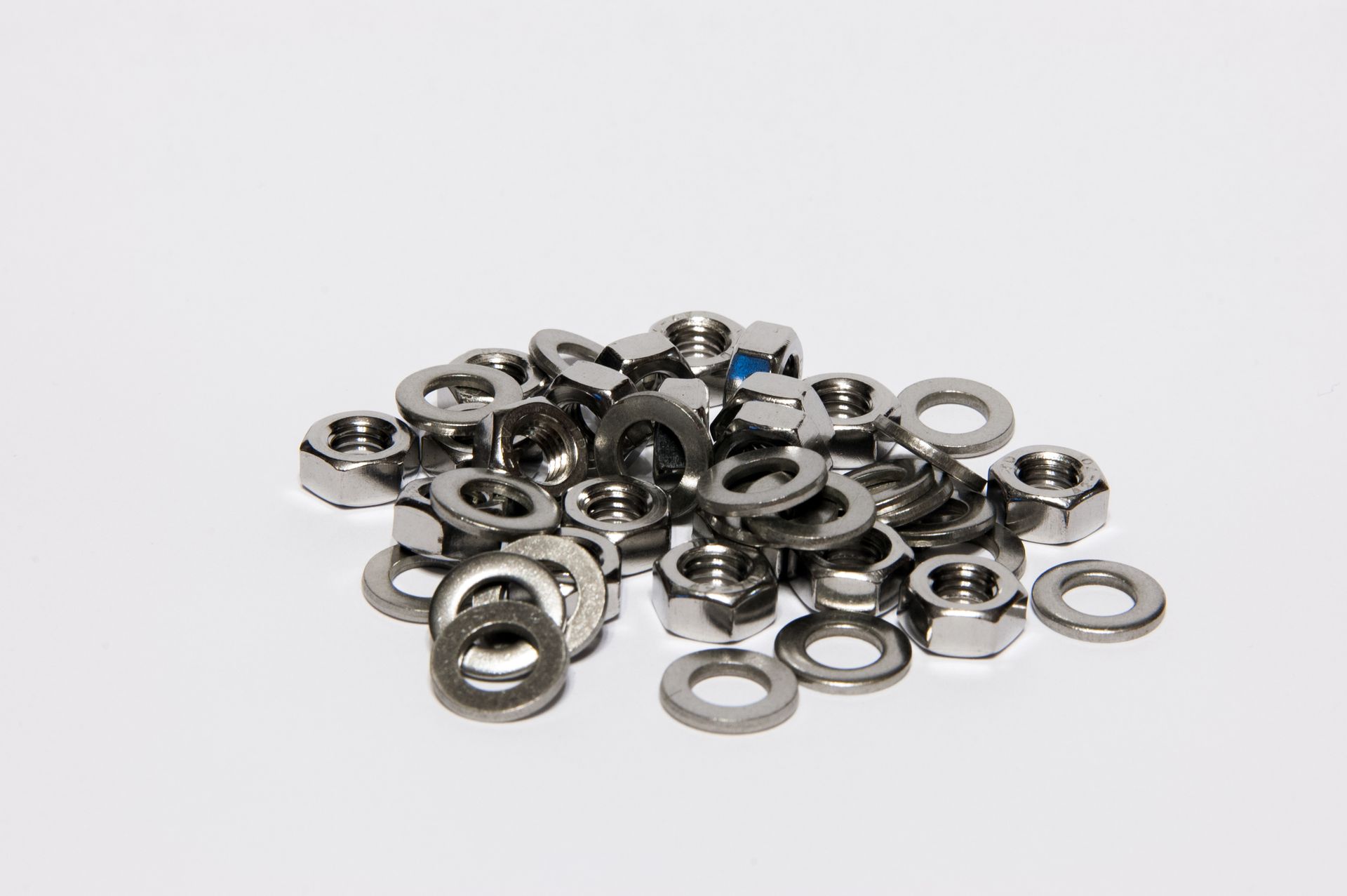 A pile of silver metal washers and nuts on a white background