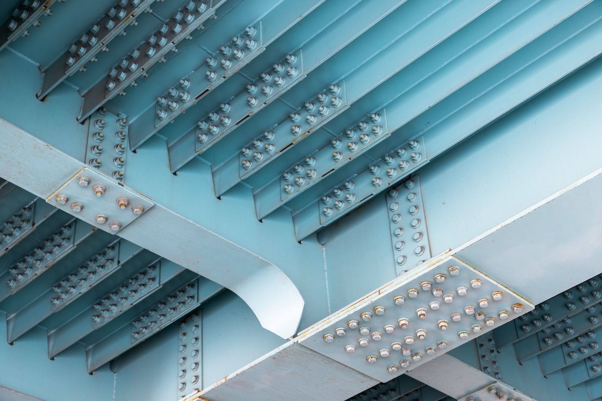 Close-up of blue steel beams with rows of rivets and diagonal supports in an industrial structure