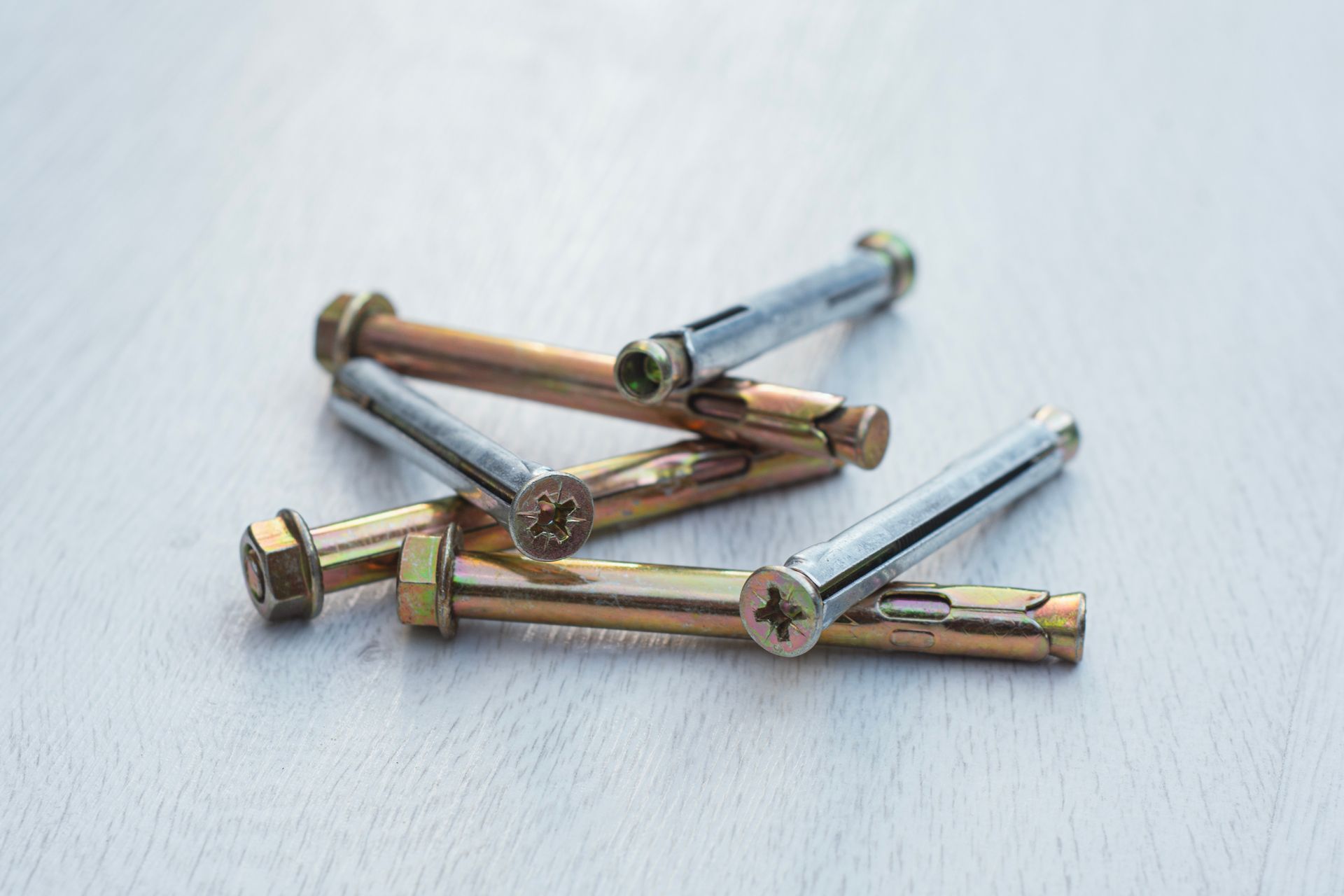 Assorted metal screws and bolts scattered on a light surface.