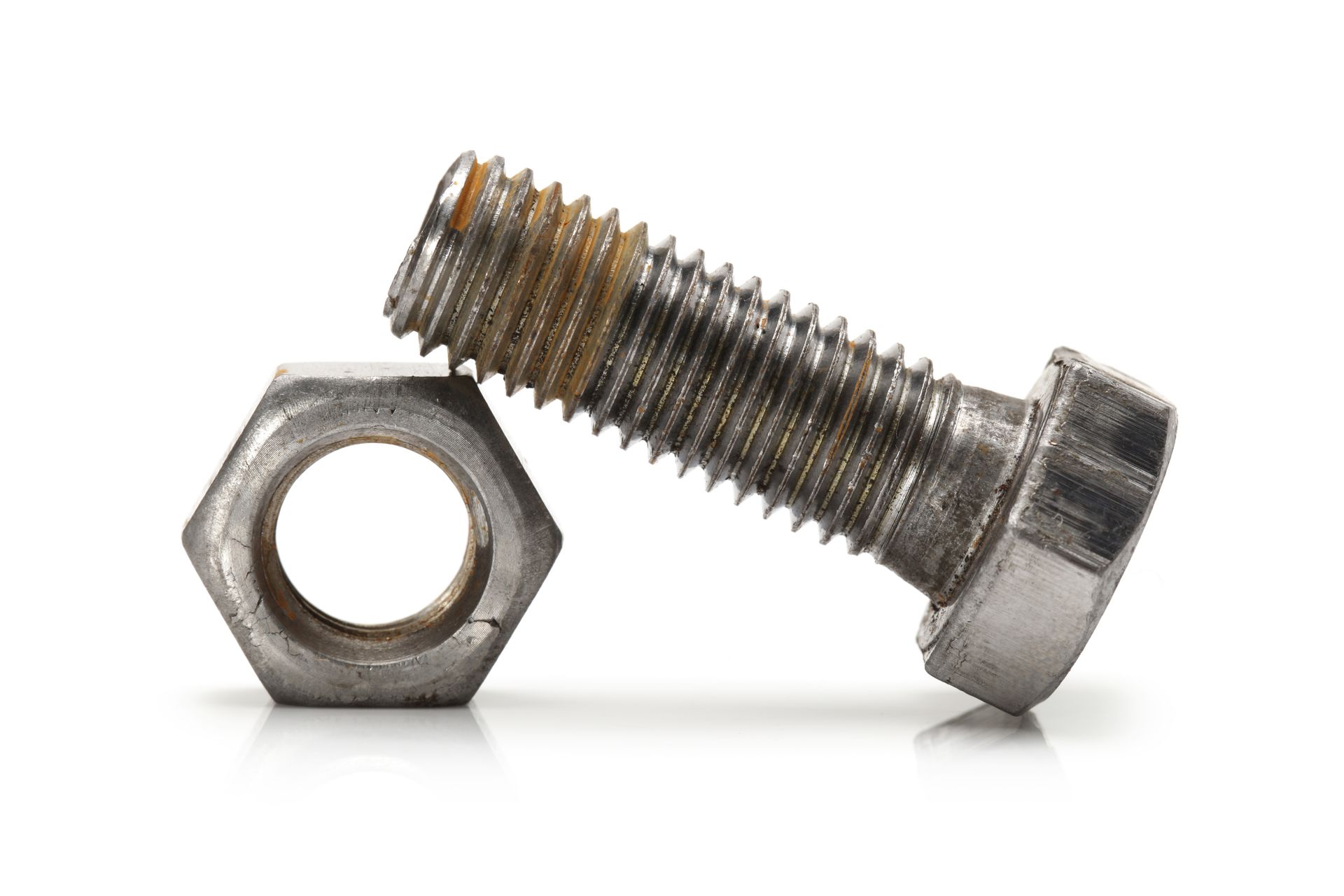 Silver bolt leaning against a hex nut on a white background