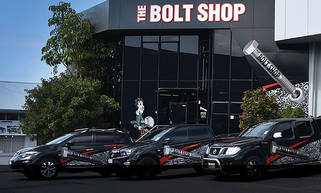 Three black cars parked outside a storefront with a red sign reading “Bolt Shop Taupo Ltd.”