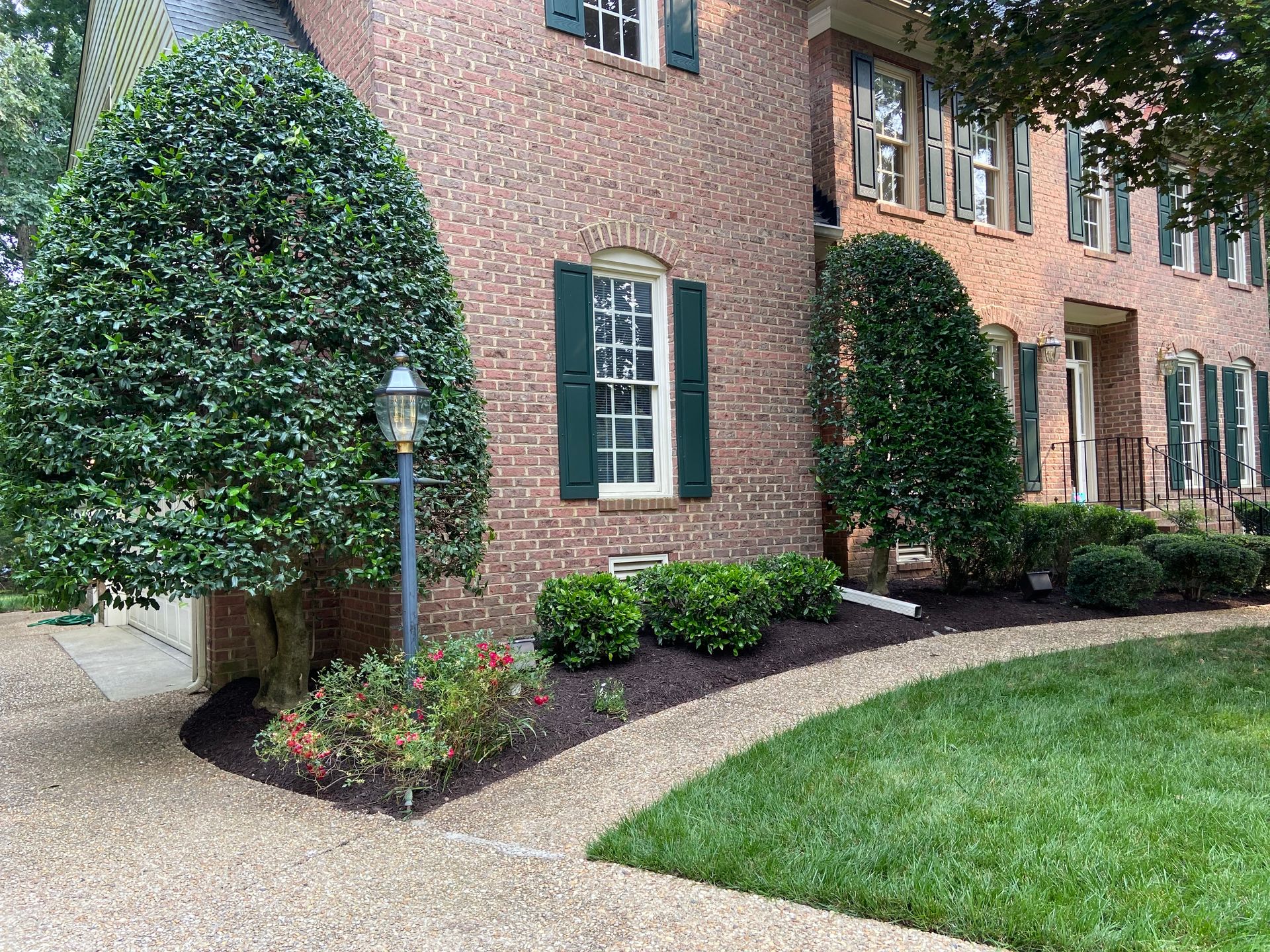 A brick house with green shutters and a walkway in front of it.