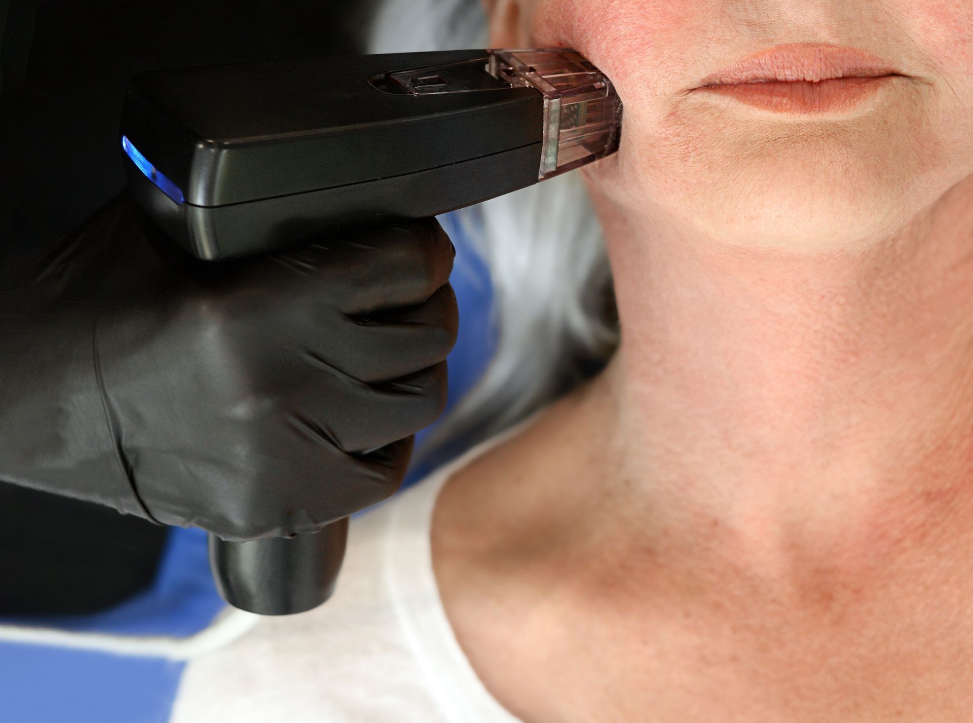 Gloved hand using a handheld scanner on a person’s neck during a medical checkup