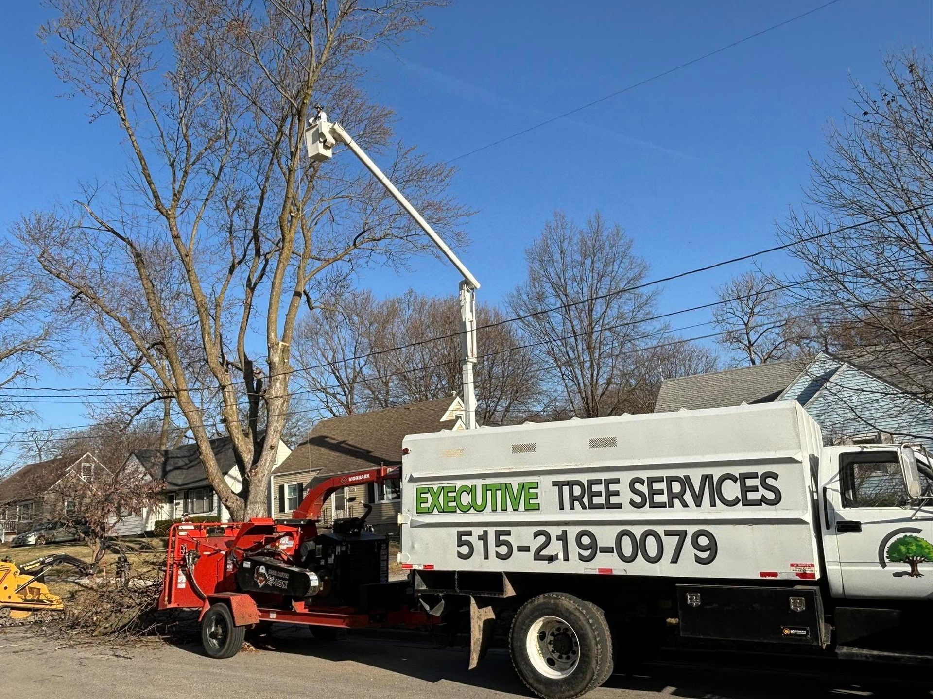 A white truck is parked next to a tree chipper.