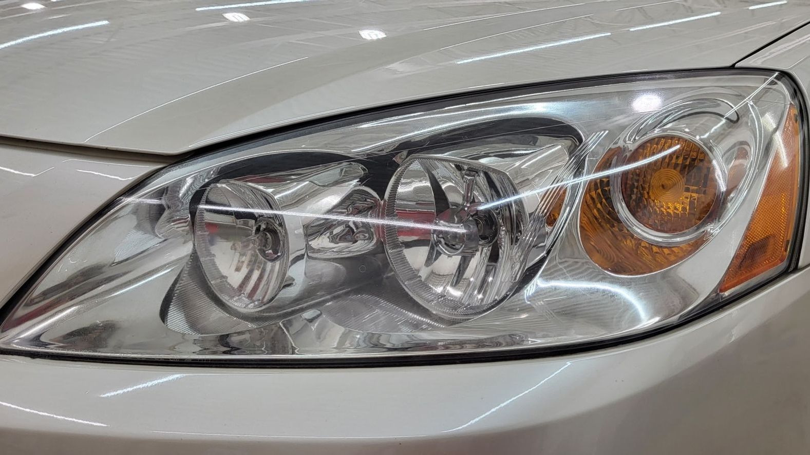 A close up of a car headlight on a white car.