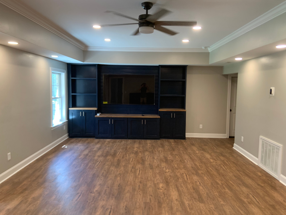 Spacious empty living room with wood floors, gray walls, and a dark built-in media cabinet.