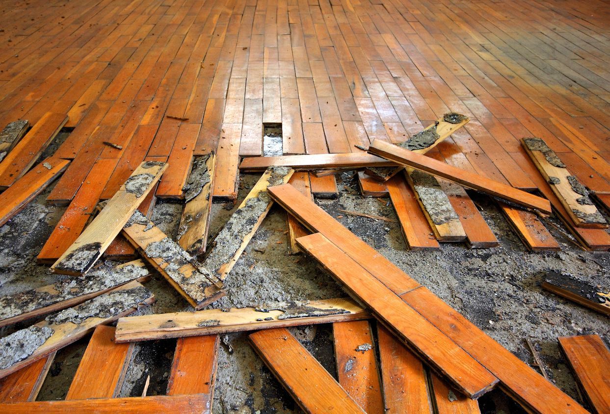 Wooden floor partially ripped up, revealing dark ground. Scattered planks, medium brown.