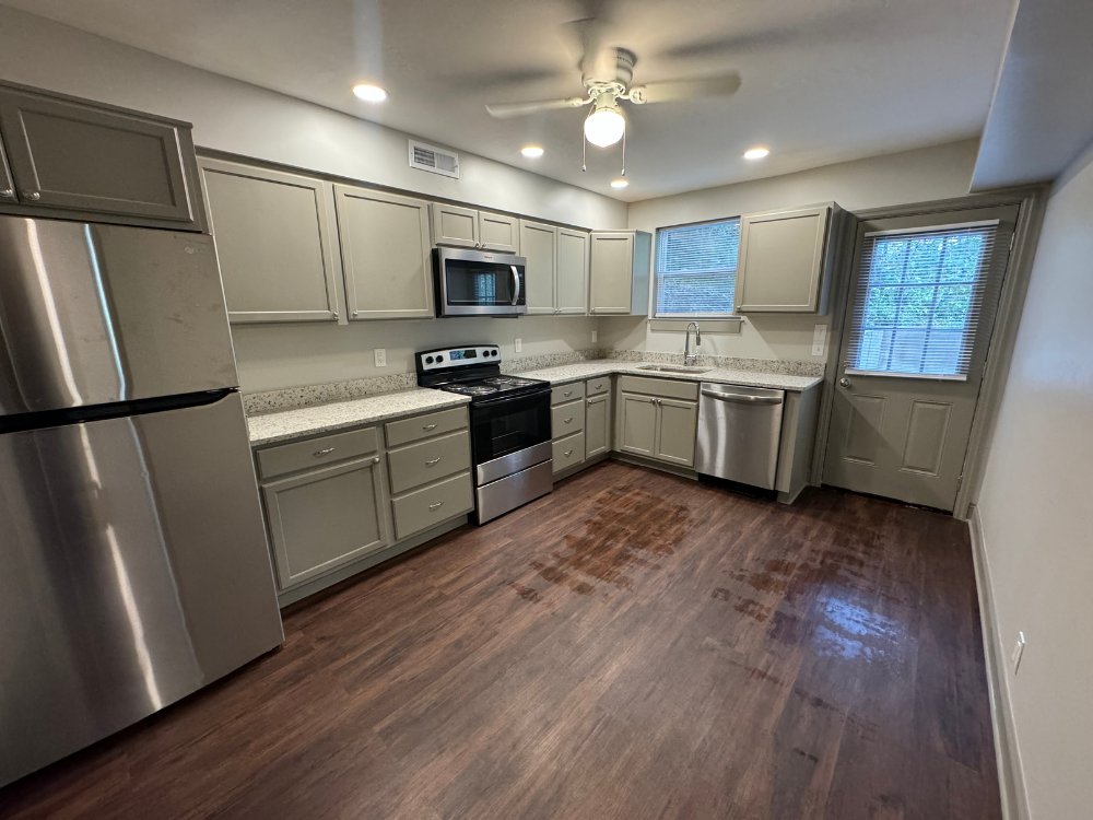 Modern kitchen with stainless steel appliances, gray cabinets, white countertops, and wood-look flooring