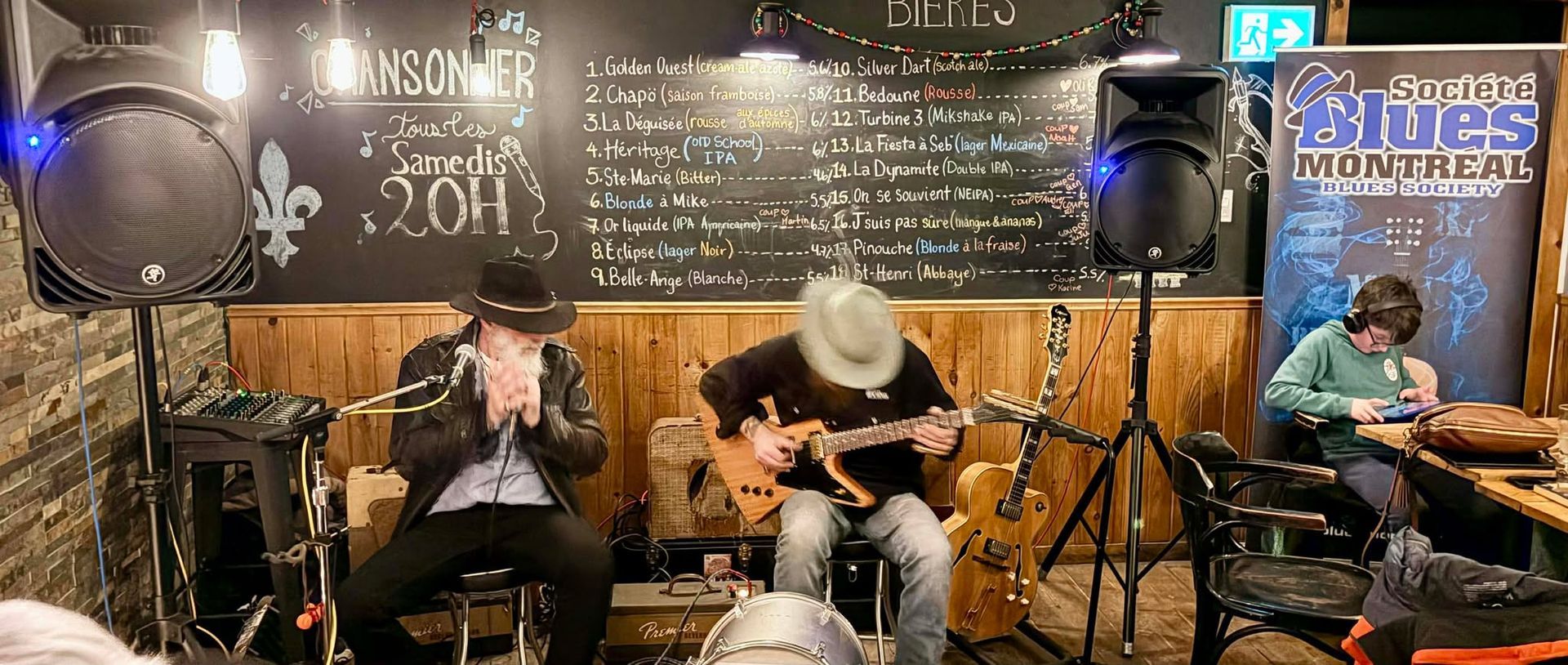 Two musicians sitting , one playing a guitar and another playing the harmonica