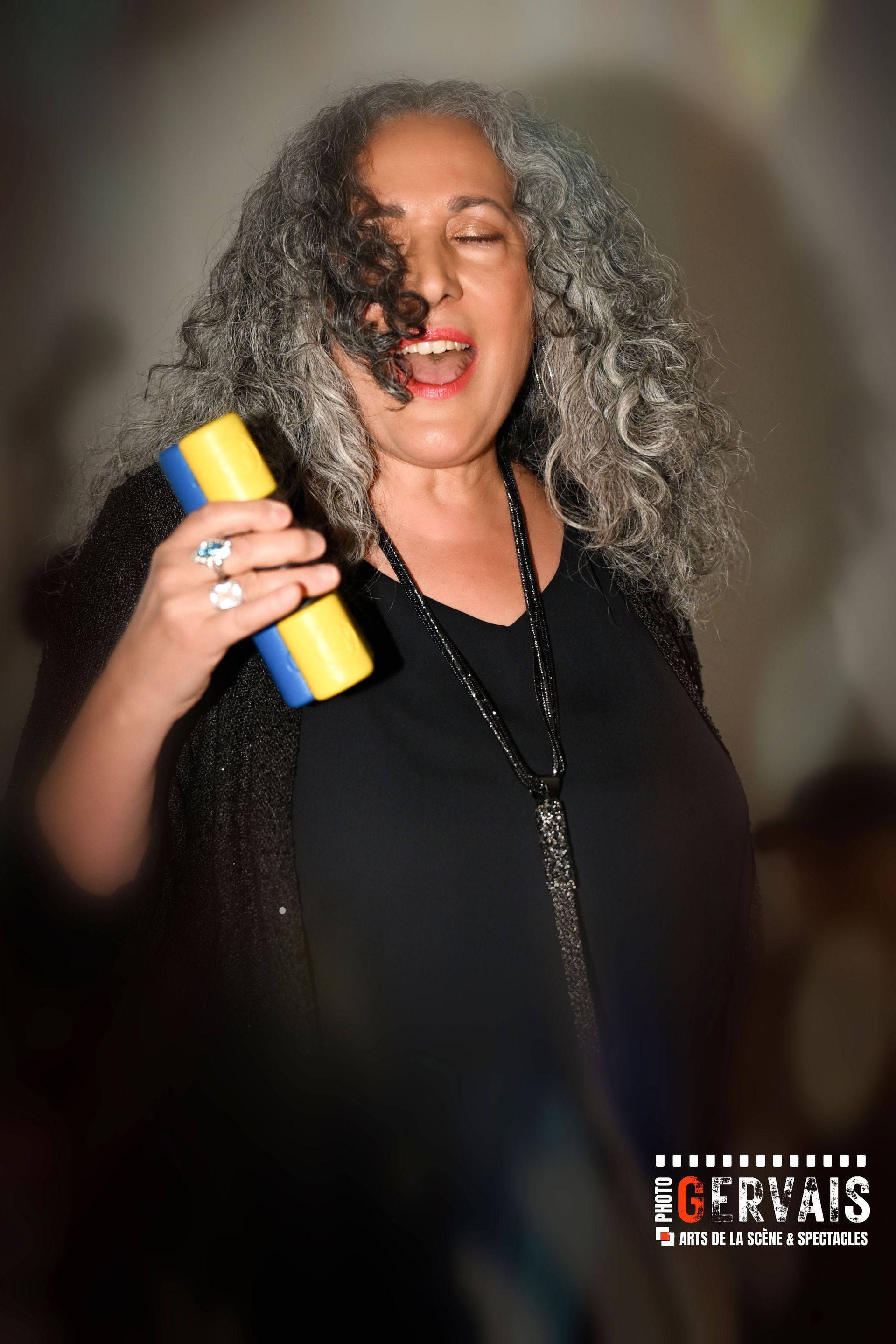 A woman dressed in black holding a shaker and singing