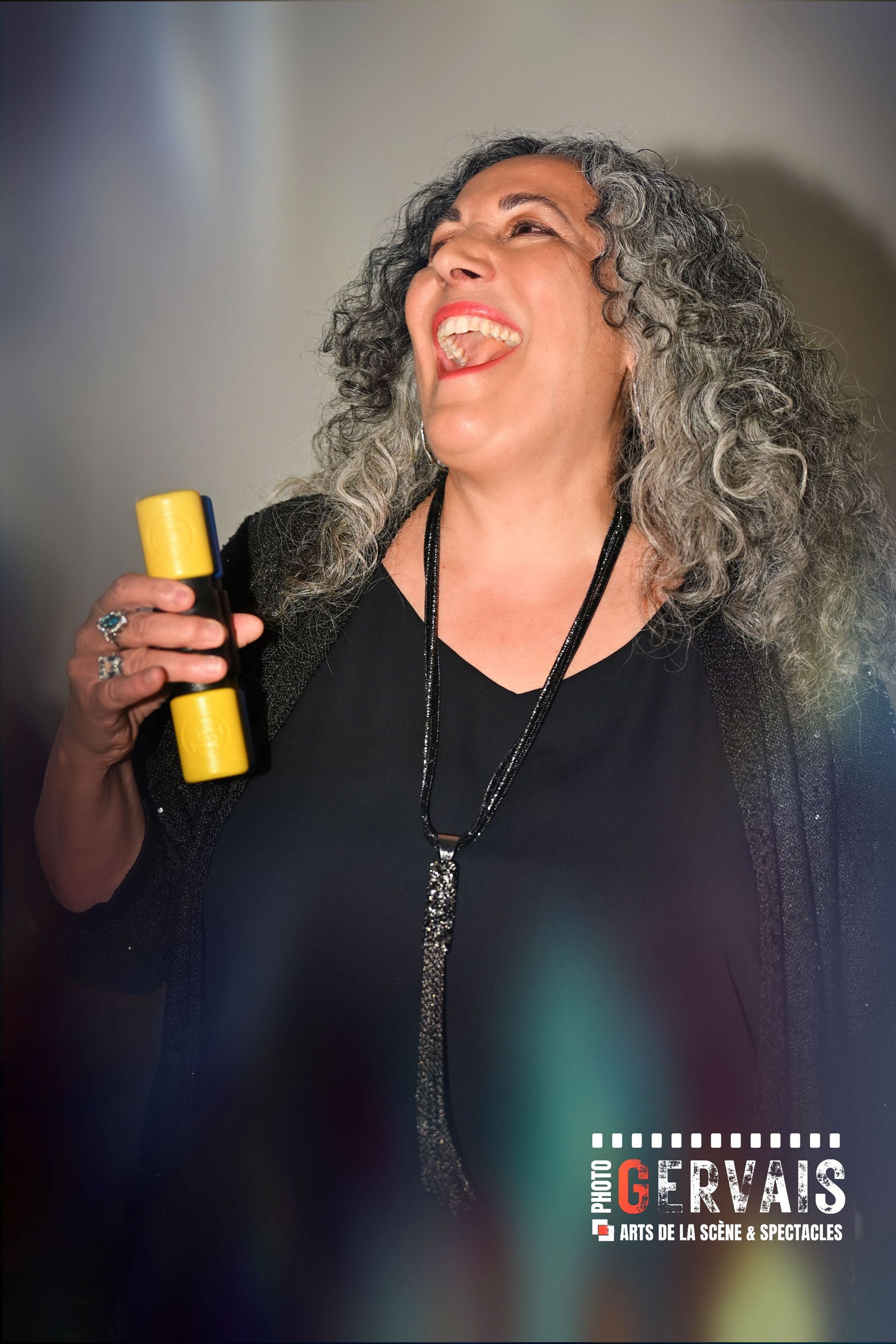 A woman dressed in black holding a shaker and singing