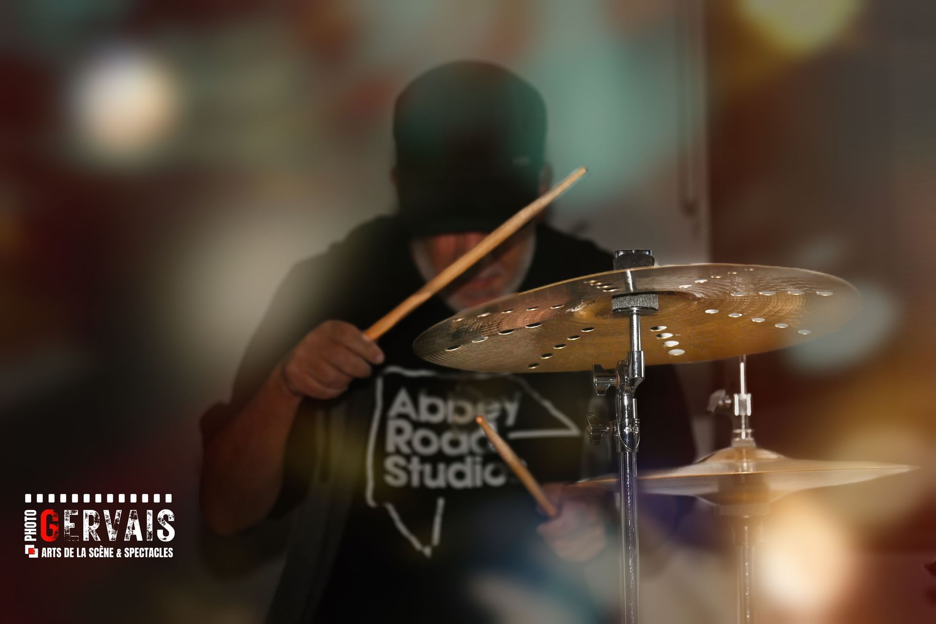 A man in a baseball cap playing the drums
