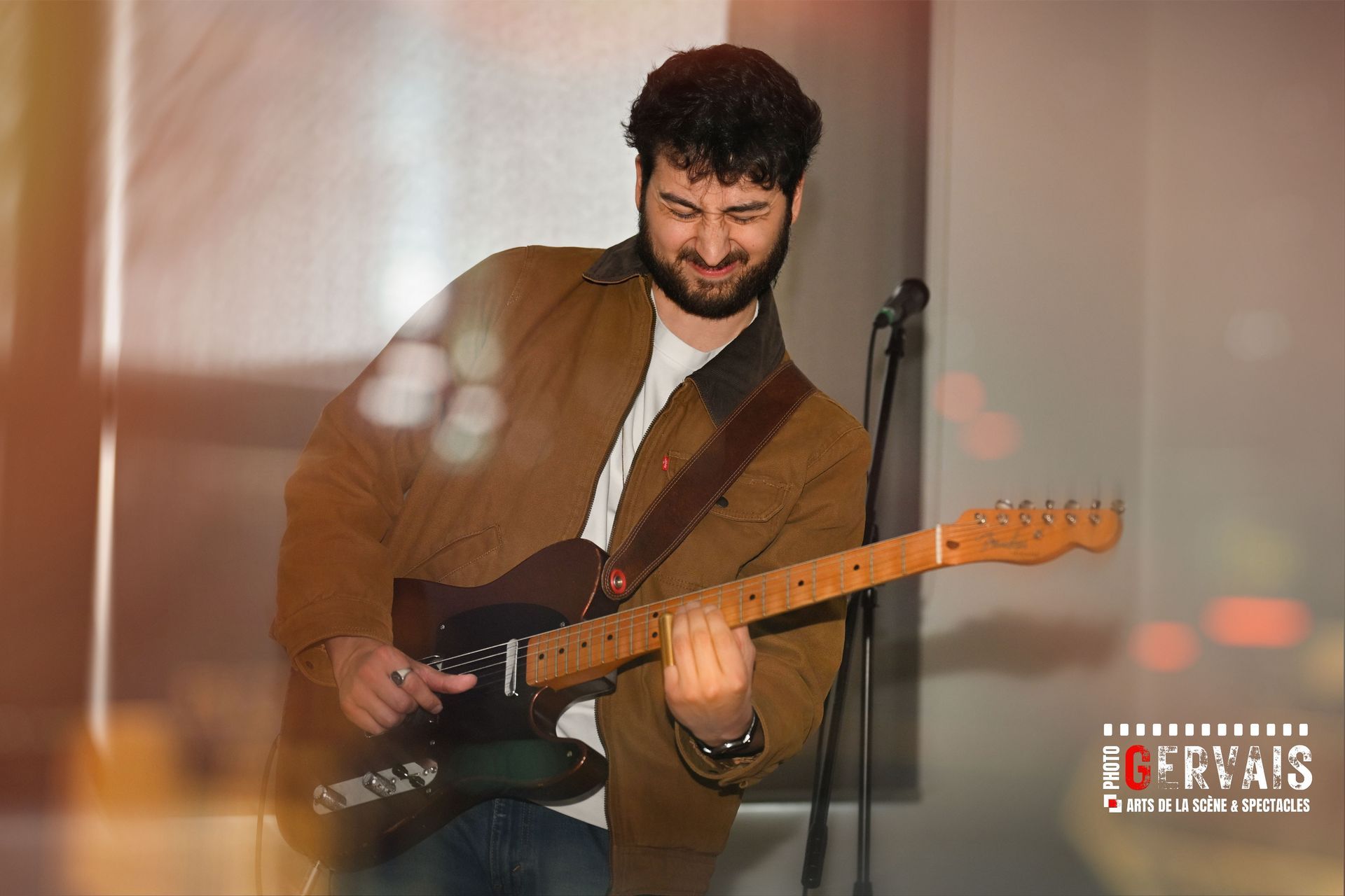 A young man in a beard playing an electric guitar