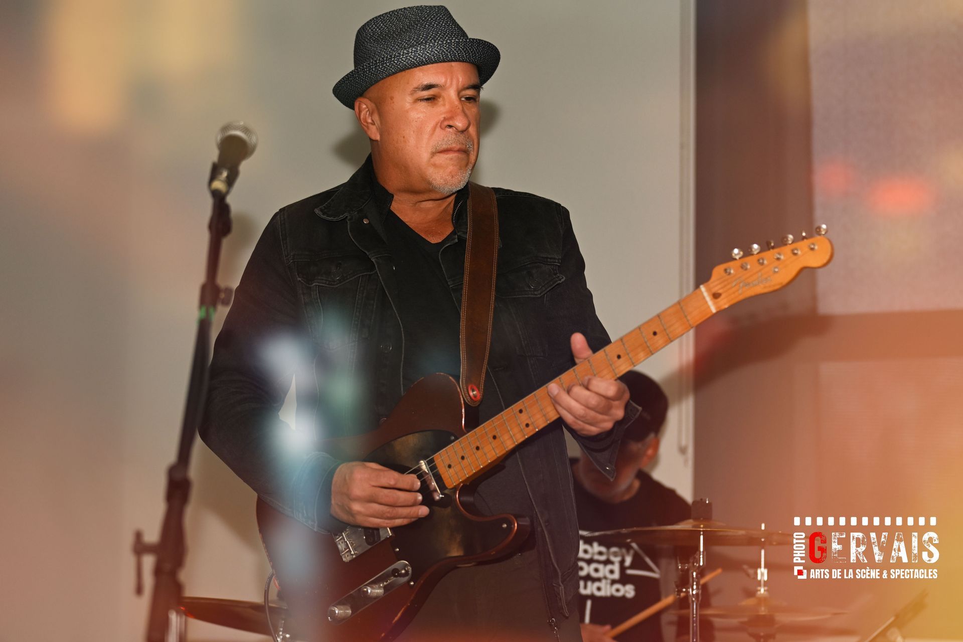 A man in a black hat playing an electric guitar
