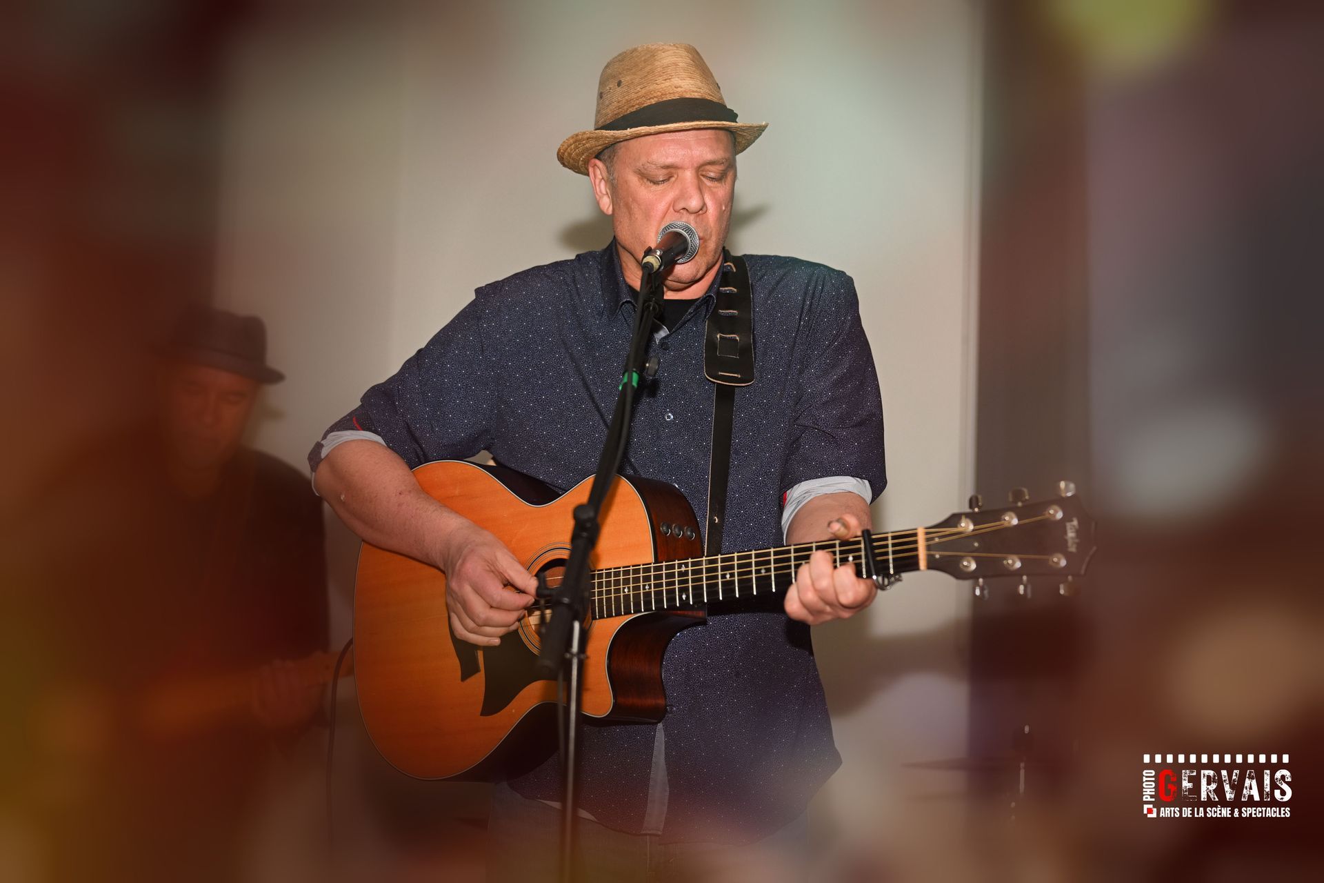 A man in a straw hat playing a guitar and singing.