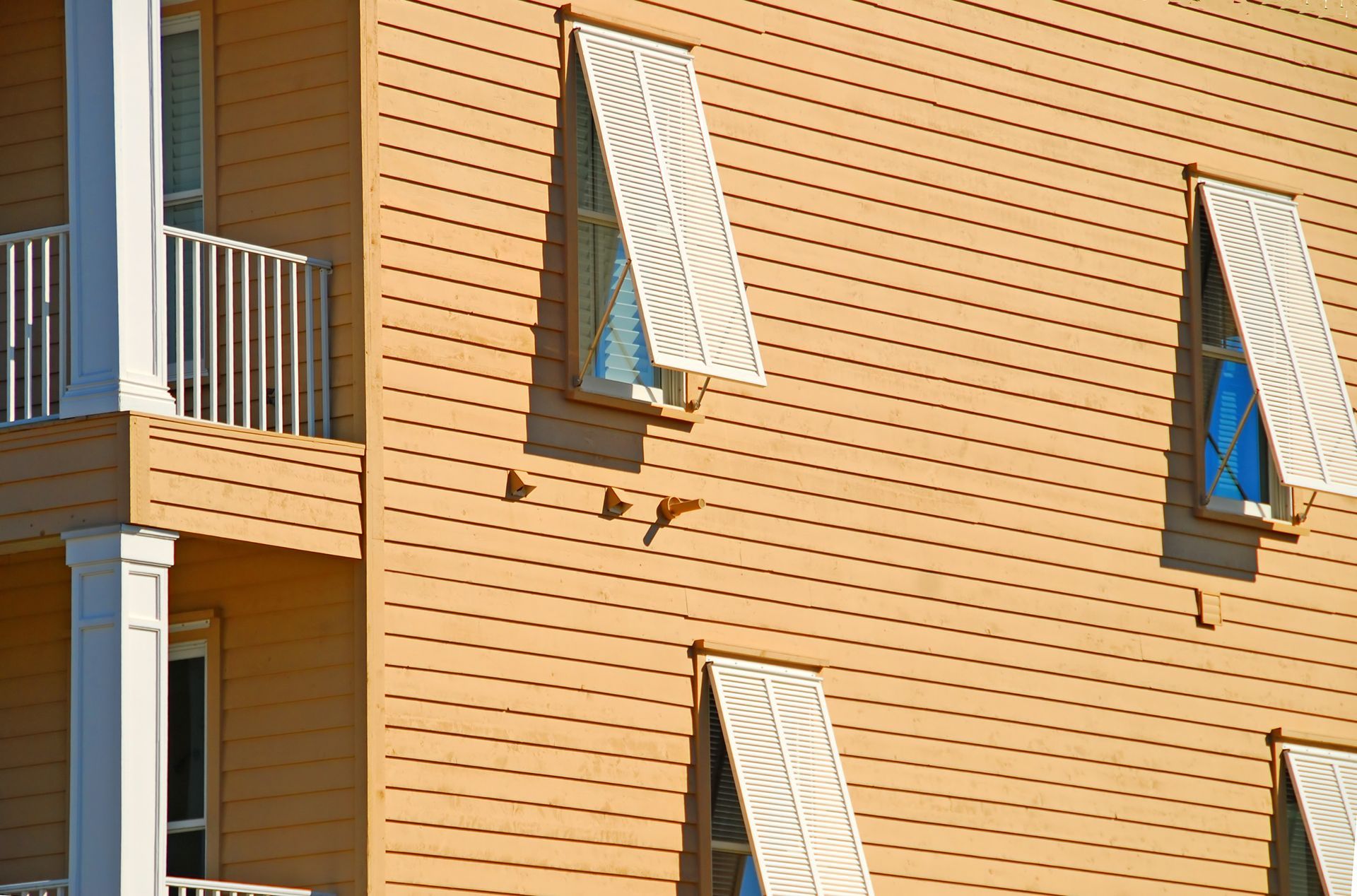 A building with a balcony and shutters on the windows.