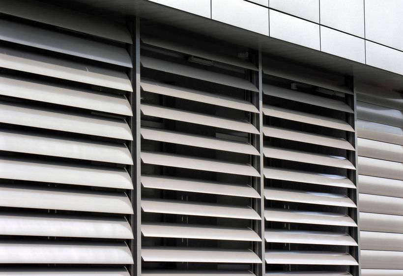 Three windows on a white building with shutters on them