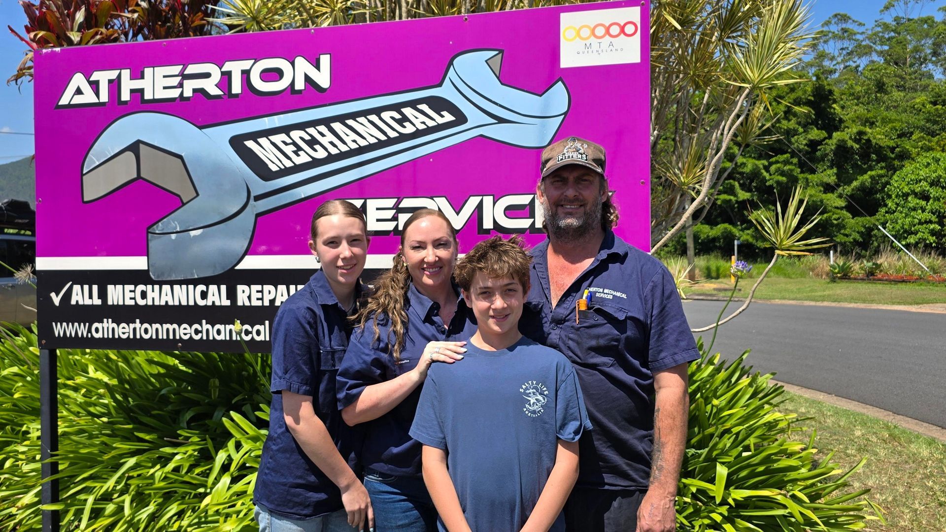 Family Stands In Front Of A Mechanic Shop Sign — Atherton Mechanical Services in Atherton, QLD