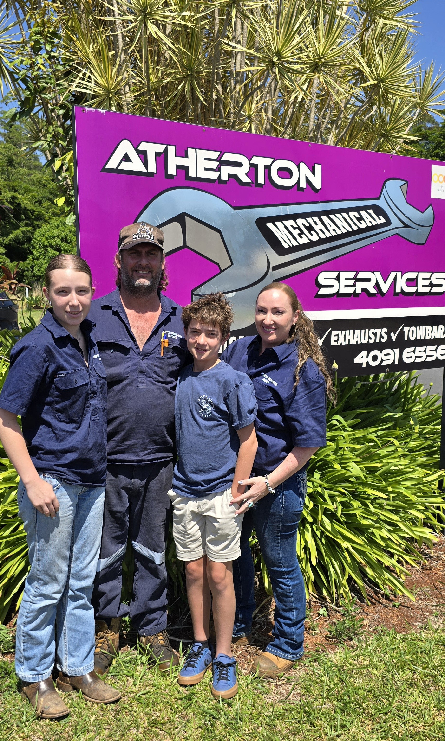 Family Stands In Front Of A Mechanic Shop Sign — Atherton Mechanical Services in Atherton, QLD
