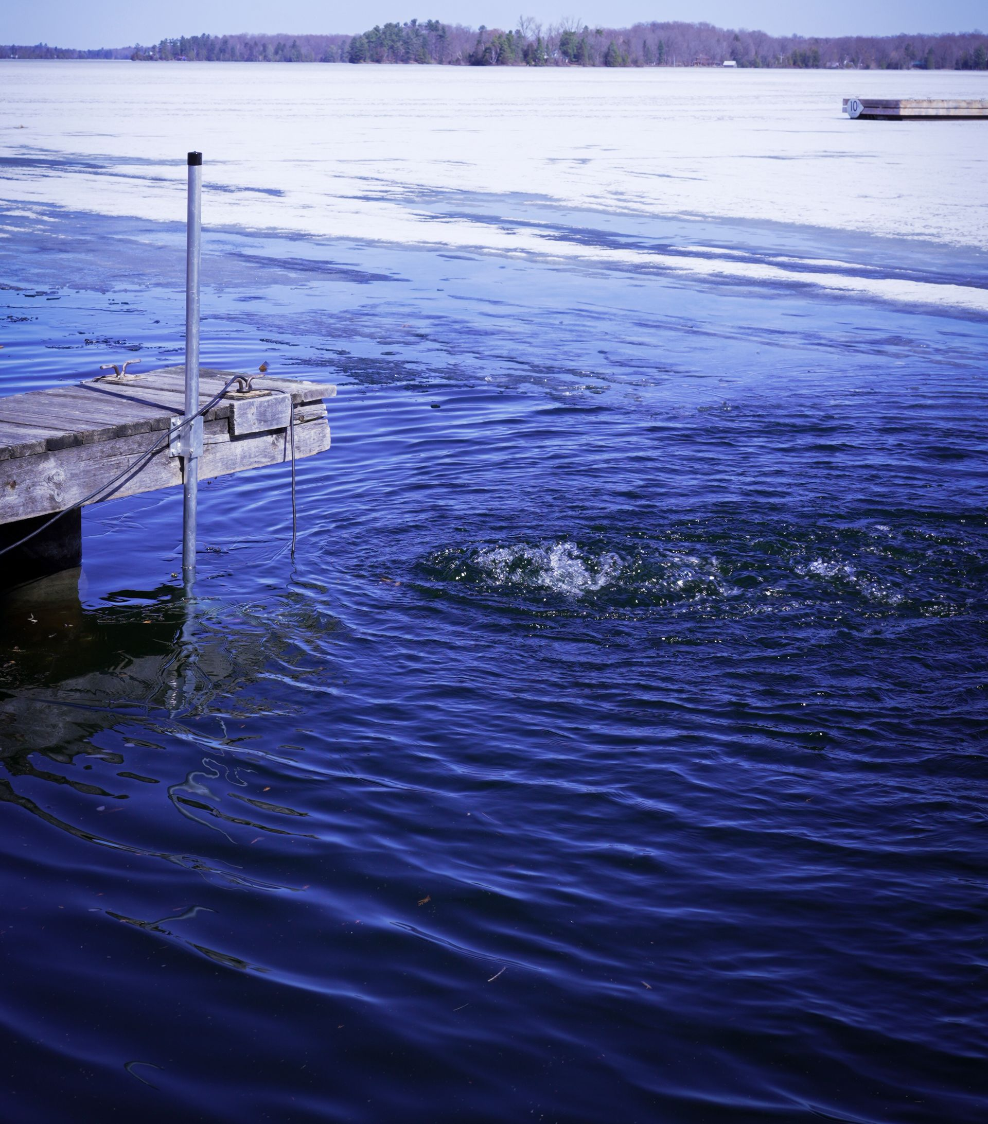 Dock de-icer circulating water beside a dock during winter freeze-up.