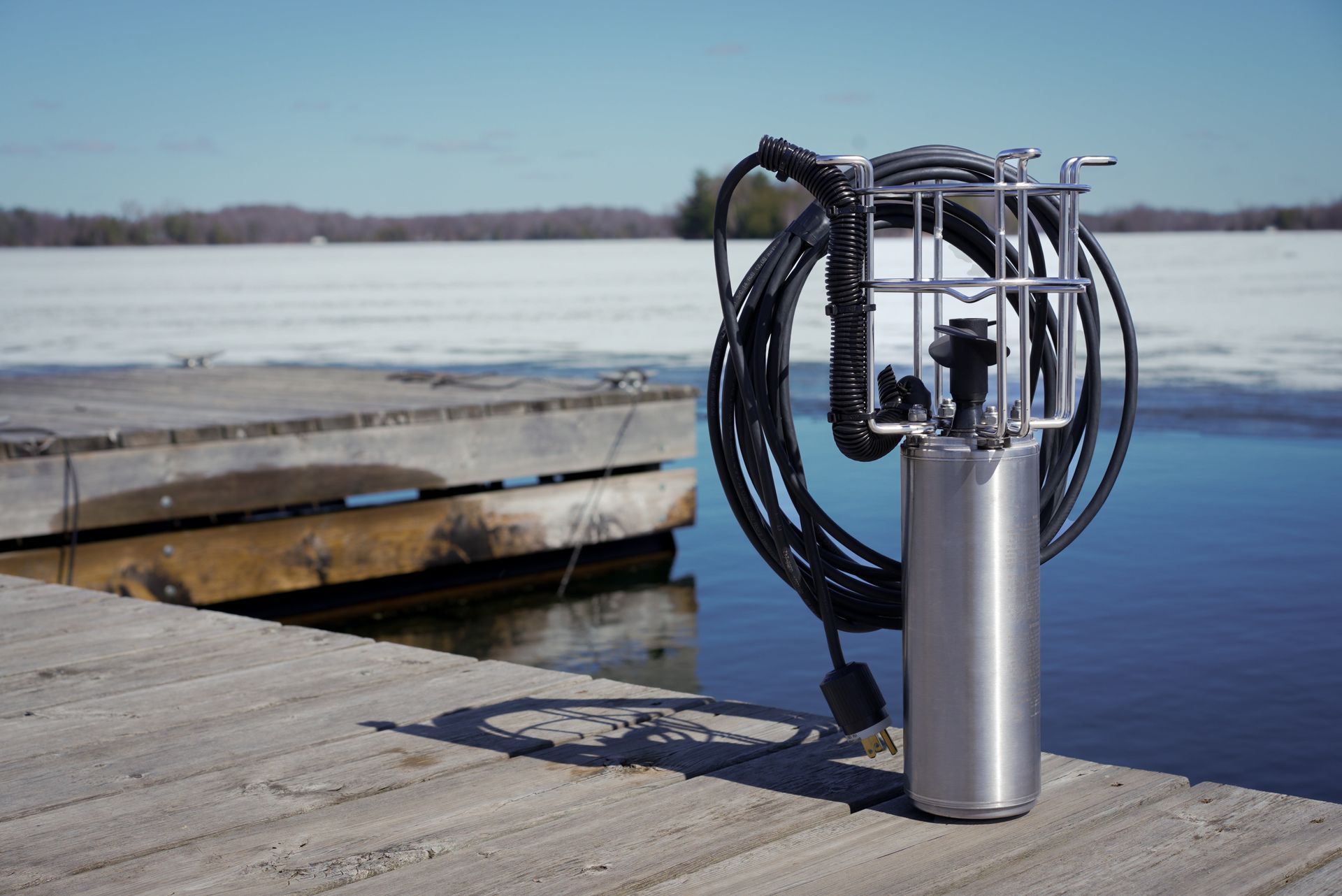 A waterfront bubbling device on a wooden dock with a lake in the background.