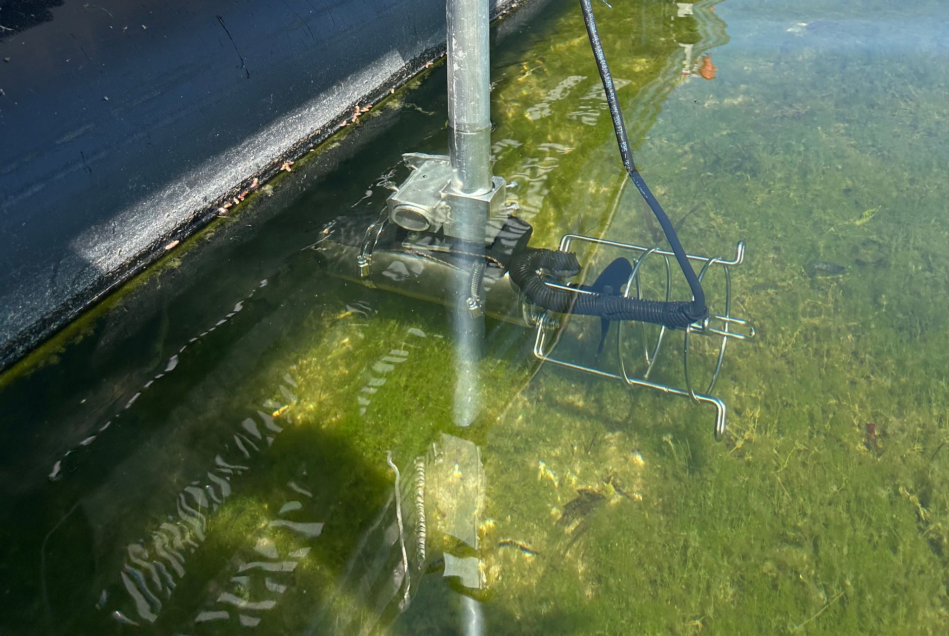 Water circulator installed beside a dock moving water through a shallow shoreline area.
