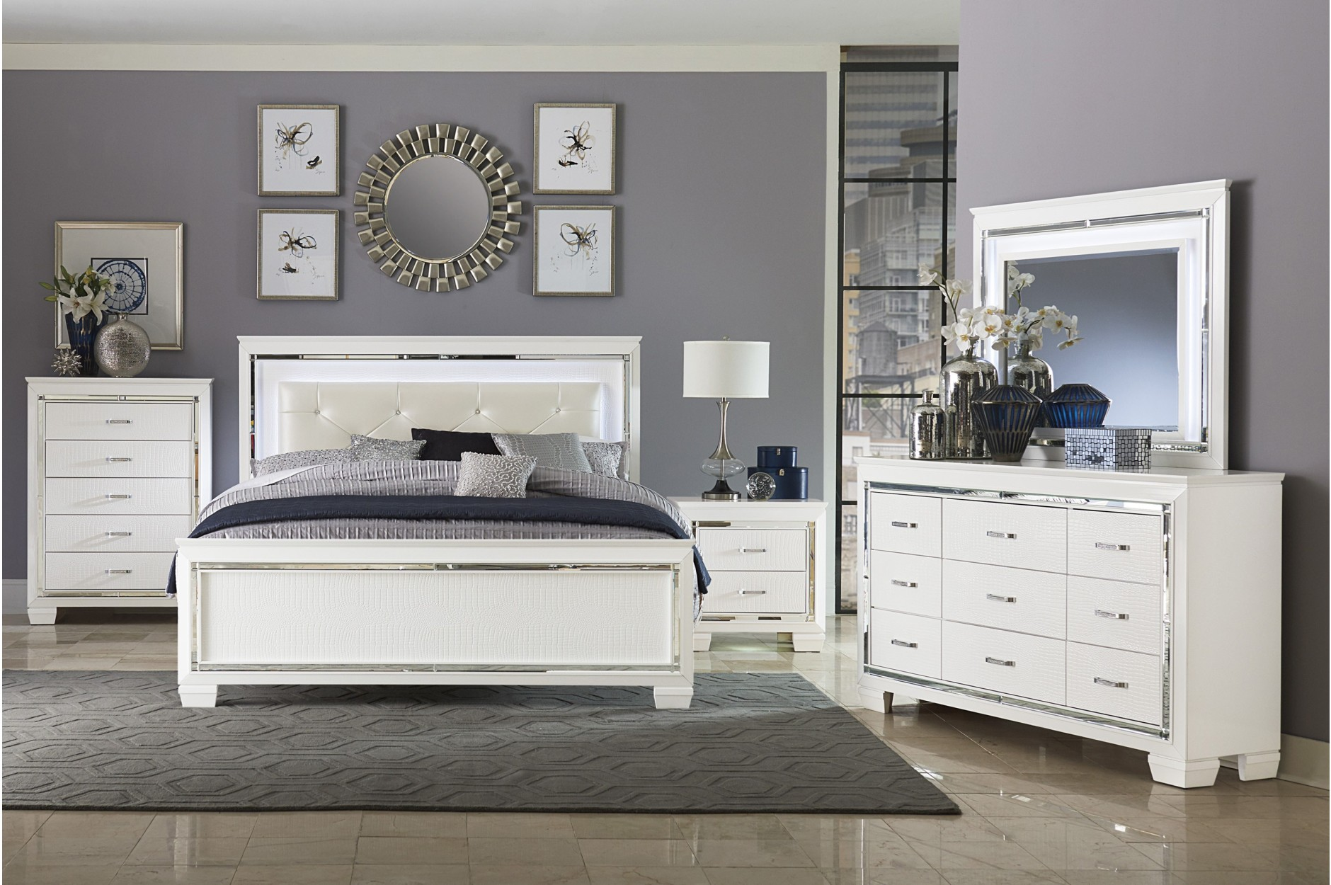 White bedroom set with bed, dresser, chest, nightstand, and mirror against a gray wall.
