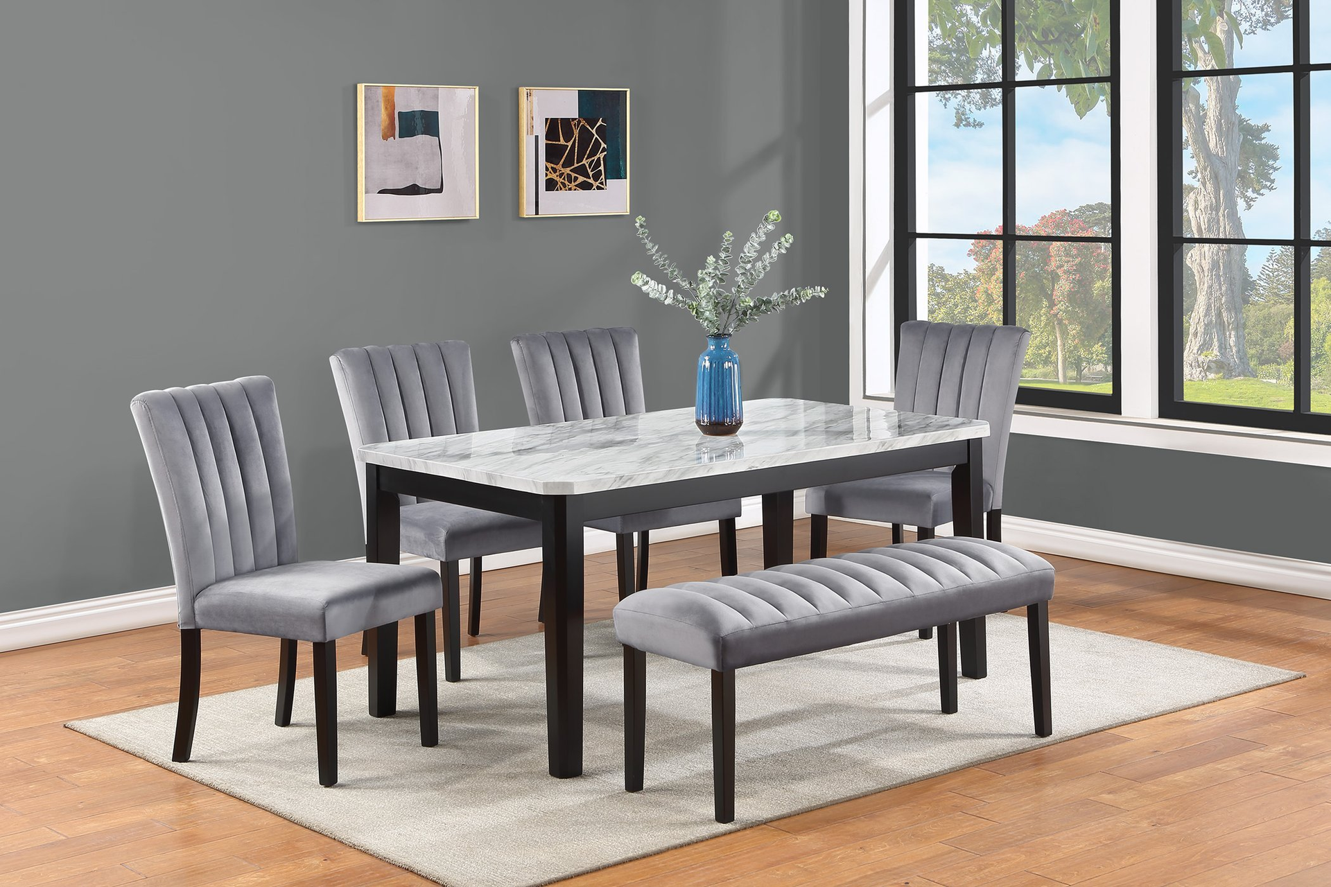 Dining room set: gray upholstered chairs/bench surround a white marble table with a vase and art on gray wall.