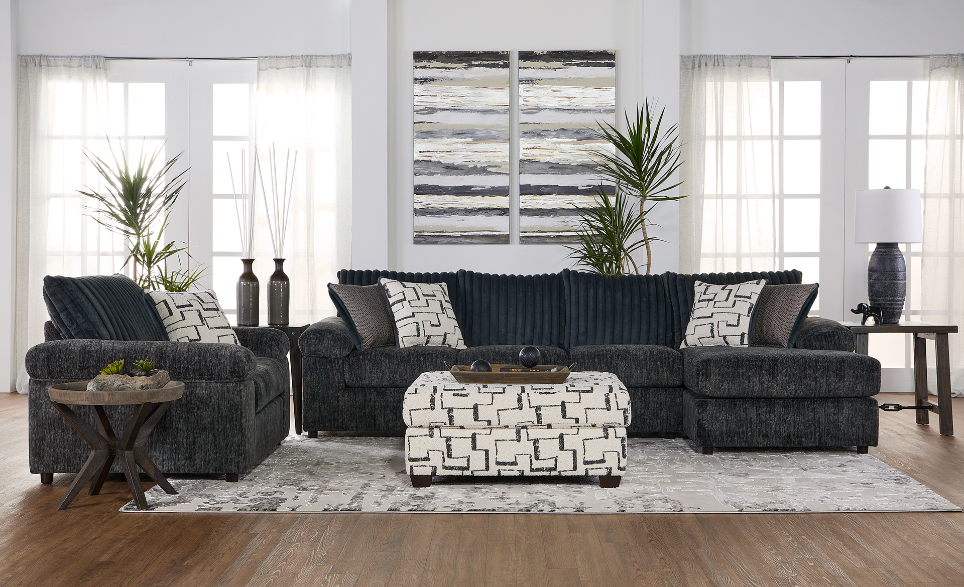 Living room with a dark blue sectional, patterned ottoman, and artwork above.