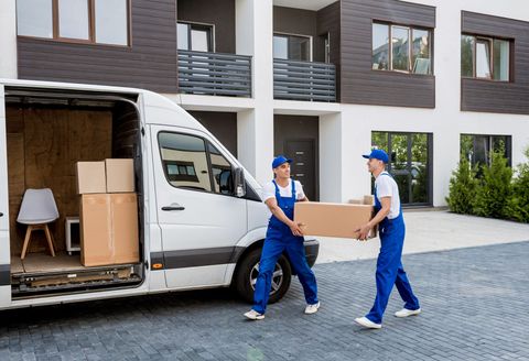 Two men are carrying boxes out of a moving van.