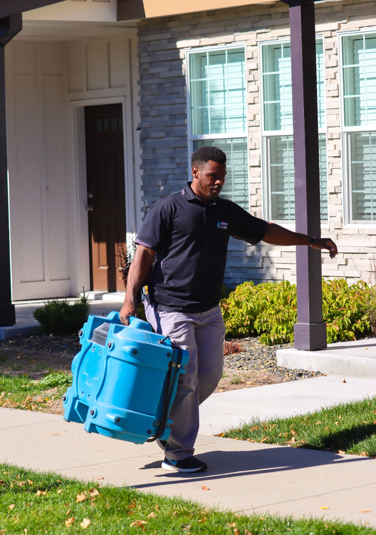 A man is walking down the sidewalk carrying a blue bag.