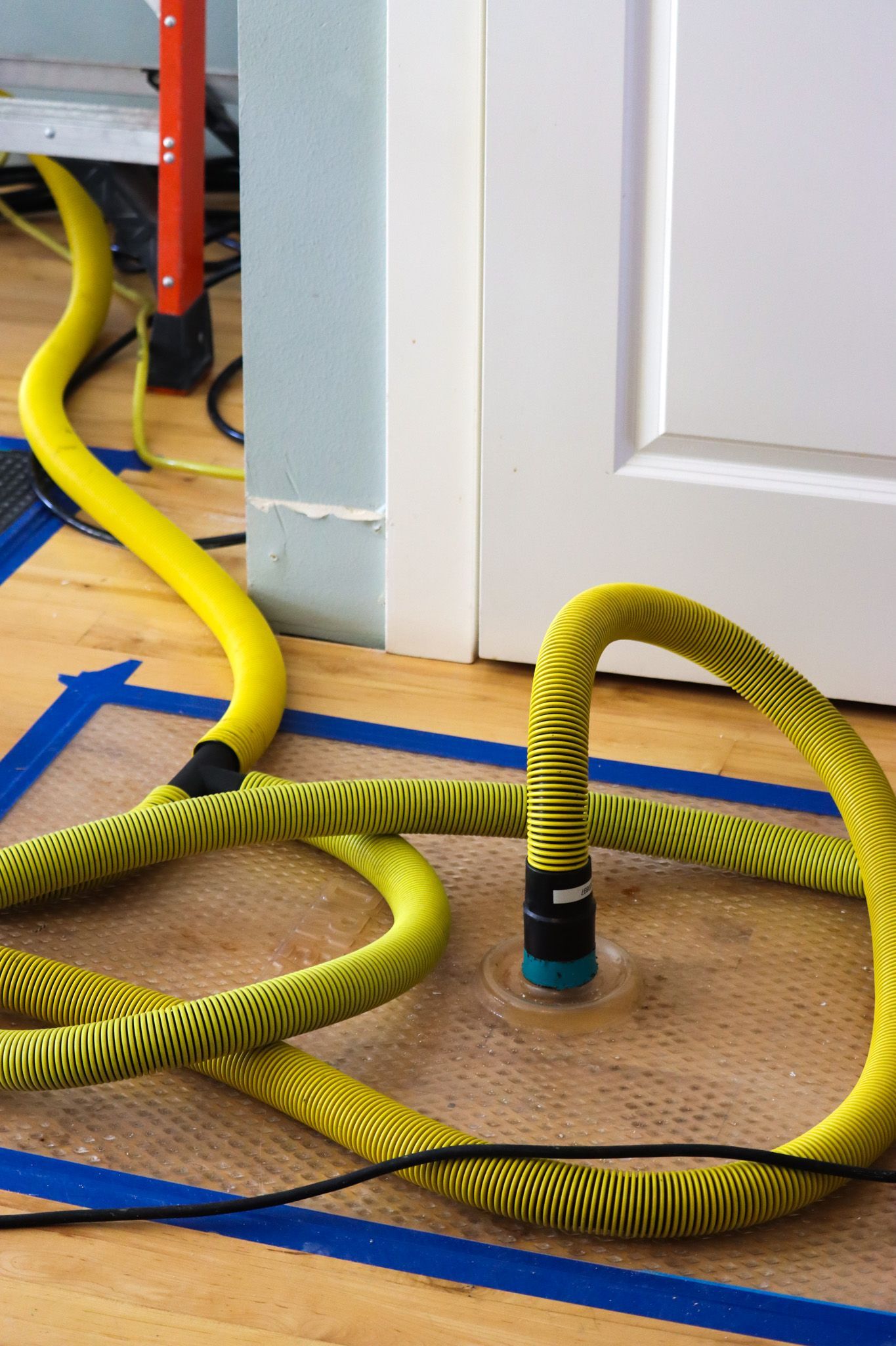 A yellow hose is laying on the floor next to a door
