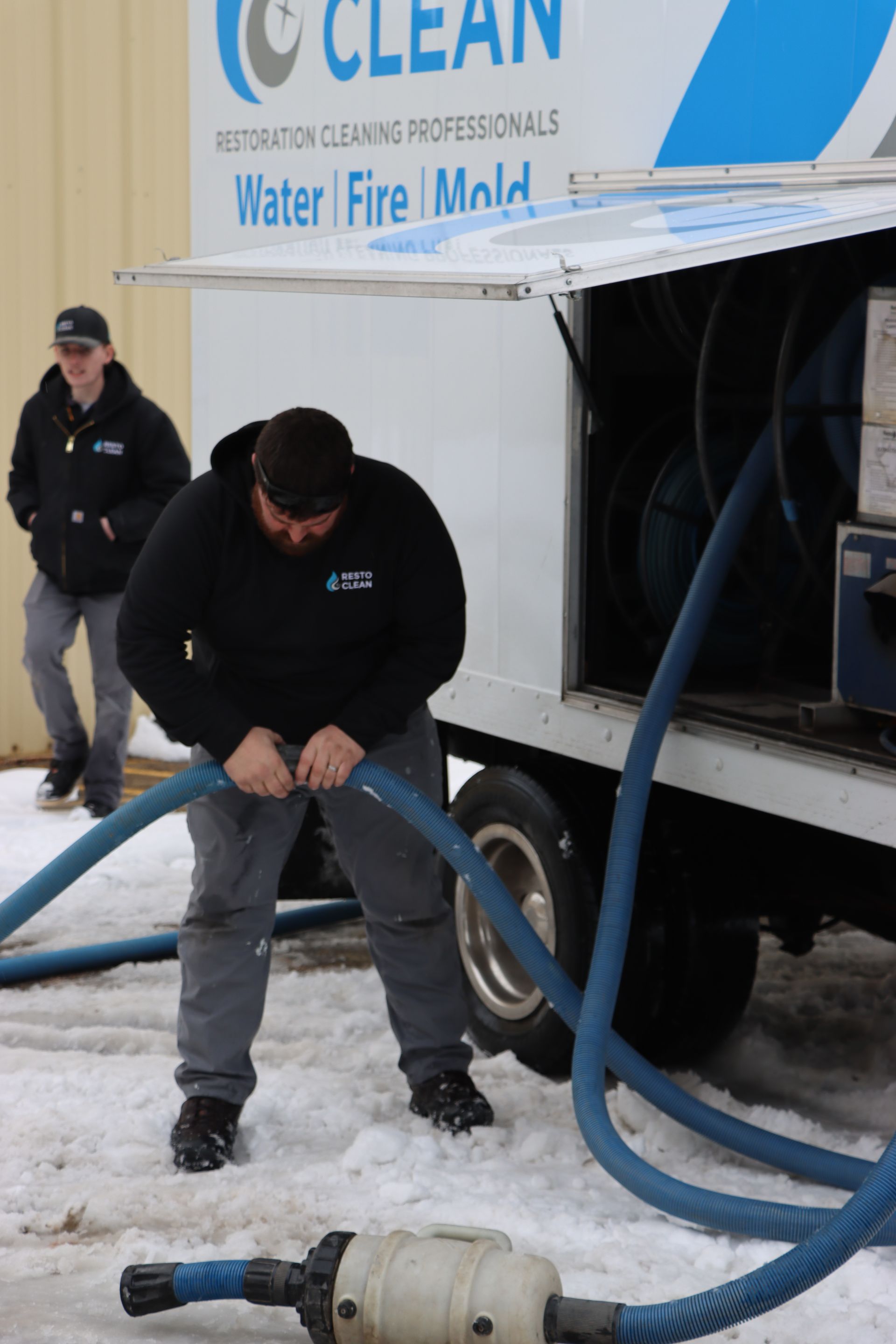 A man is working on a hose in front of a clean truck