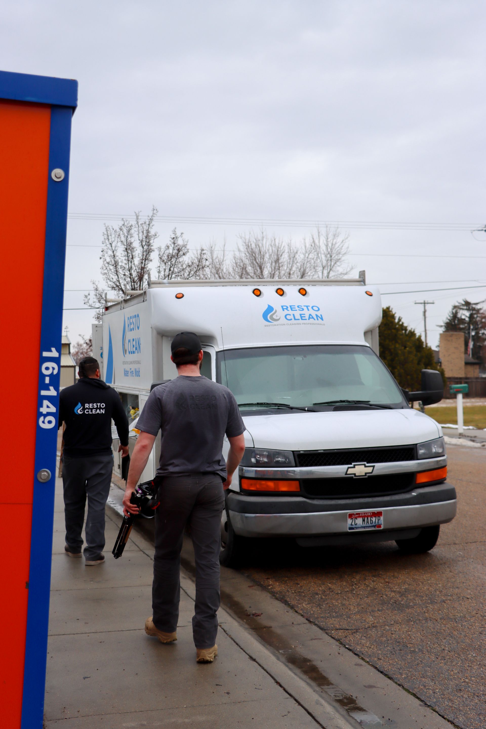 Two men are walking towards a chevrolet van with the number 161459 on it