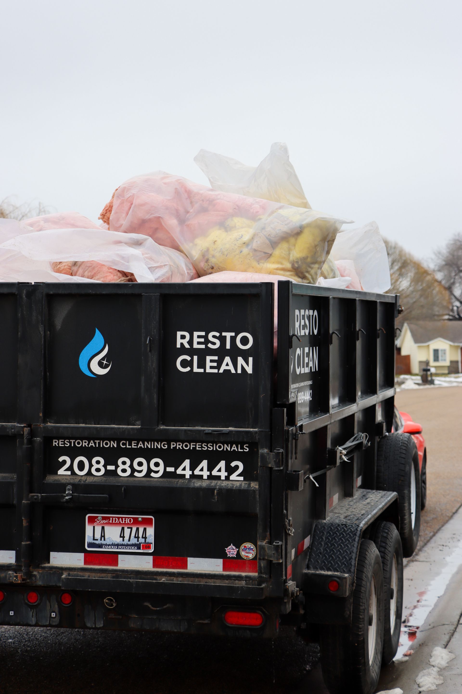 A dumpster with a lot of trash in it is parked on the side of the road.
