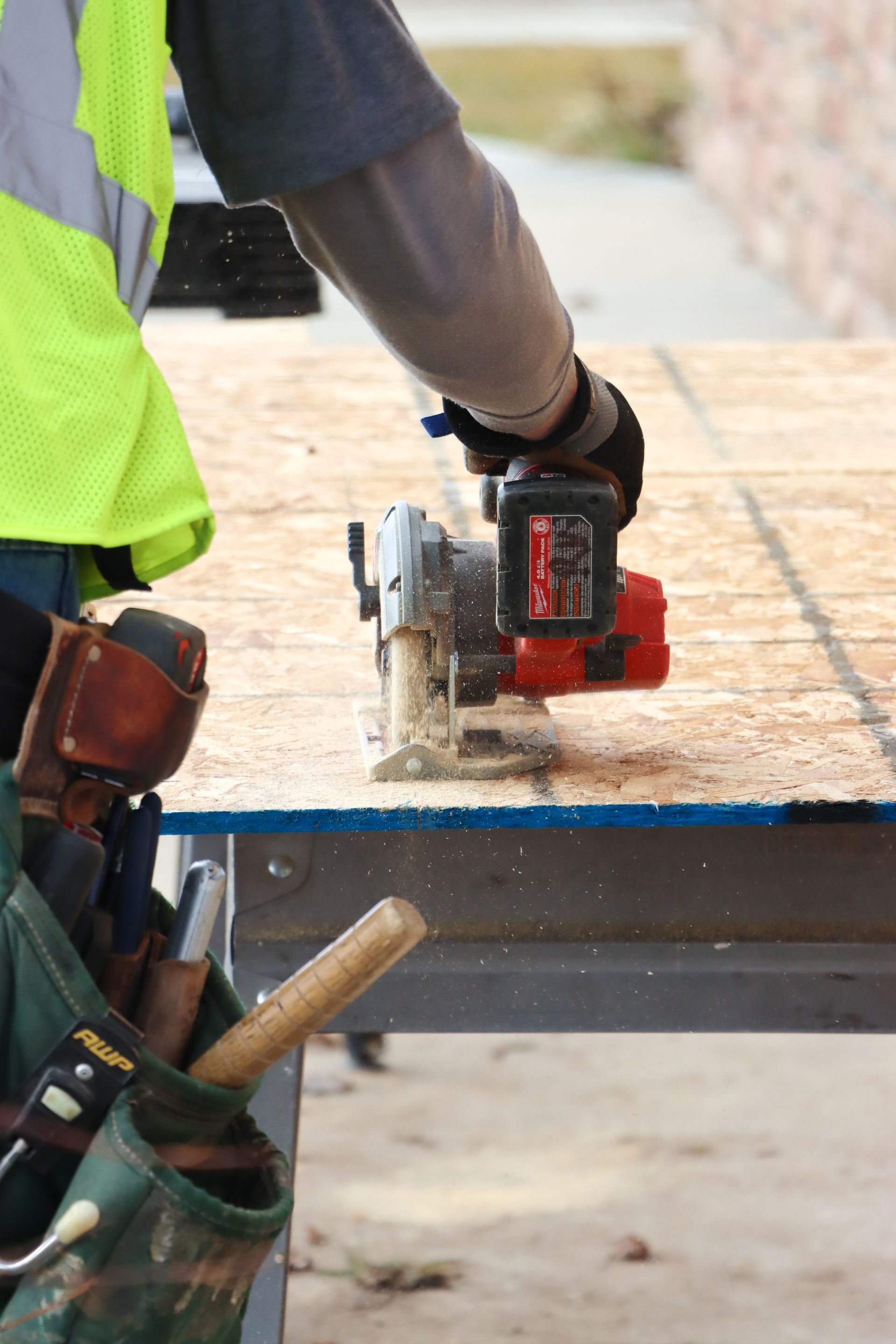 A man is using a circular saw to cut a piece of plywood.