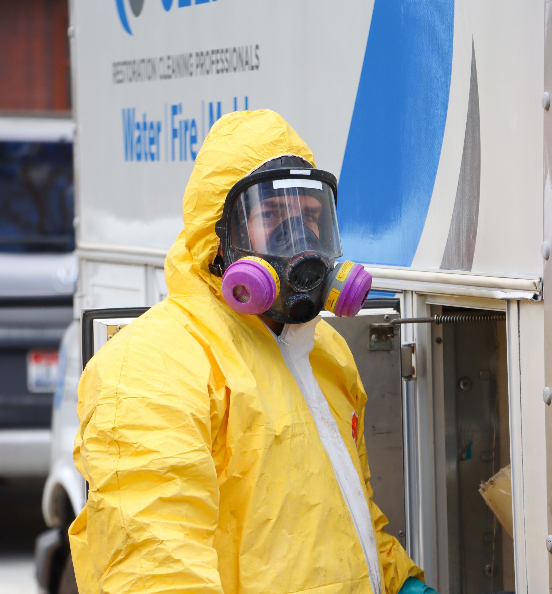 A man wearing a yellow protective suit and a gas mask