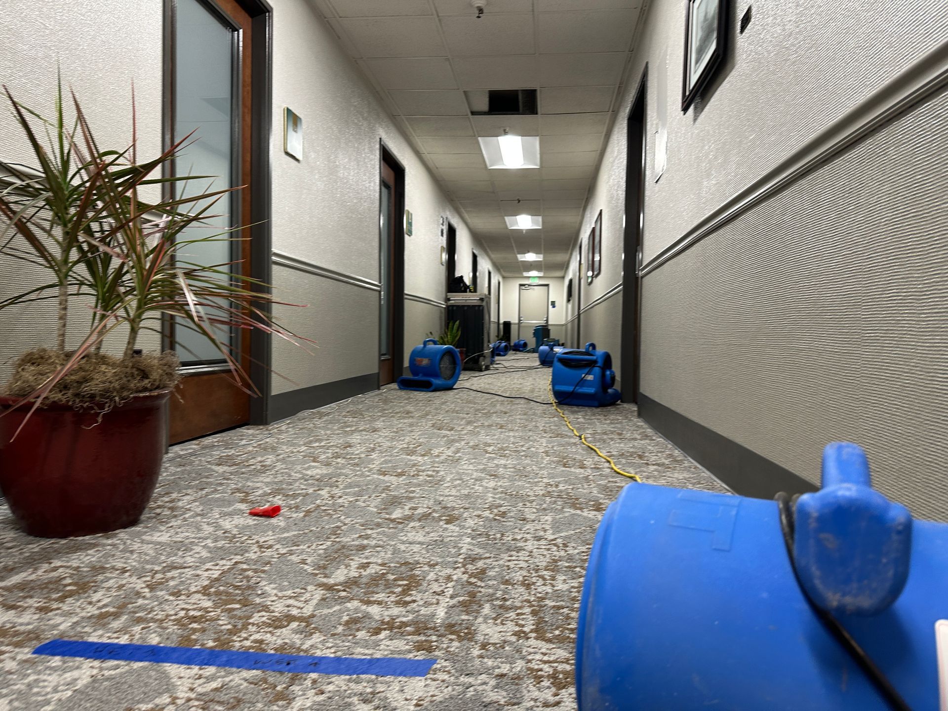 A long hallway with a blue barrel in the middle of it.