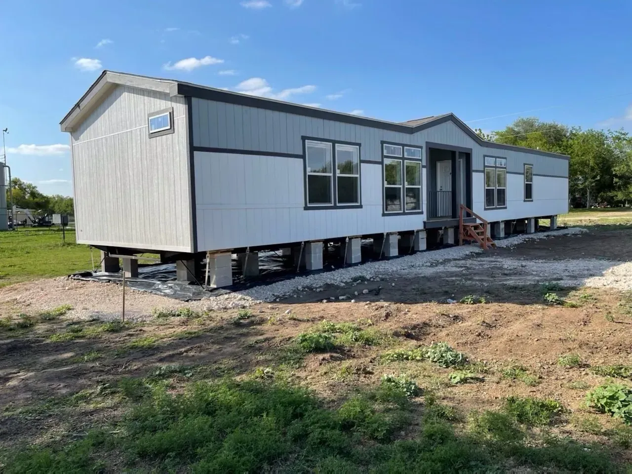 A mobile home is sitting on top of a dirt field.