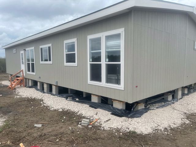 A mobile home is sitting on top of a pile of gravel in a field.