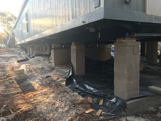 A mobile home is sitting on top of concrete pillars.