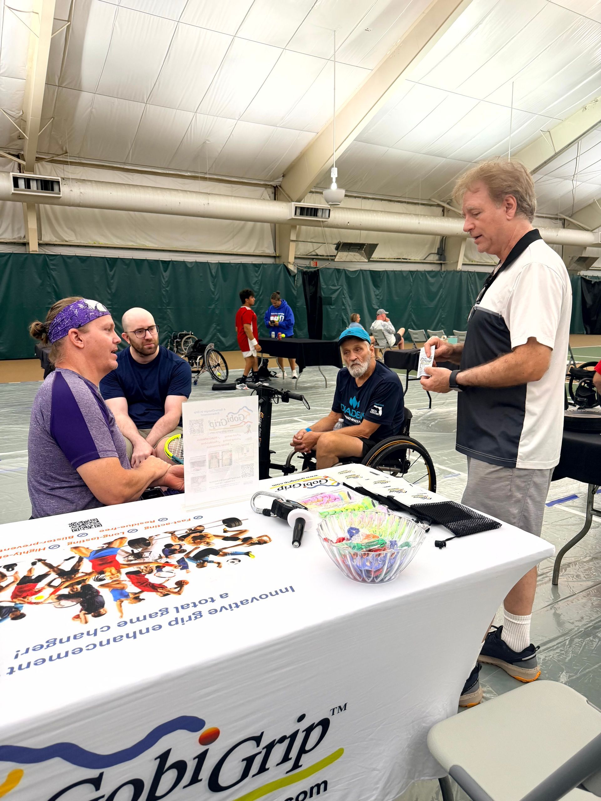 Gobi Grip inventor Dr. Mark Miller talking with wheelchair tennis players at the Gobi Grip table during the USTA Level 2 tournament