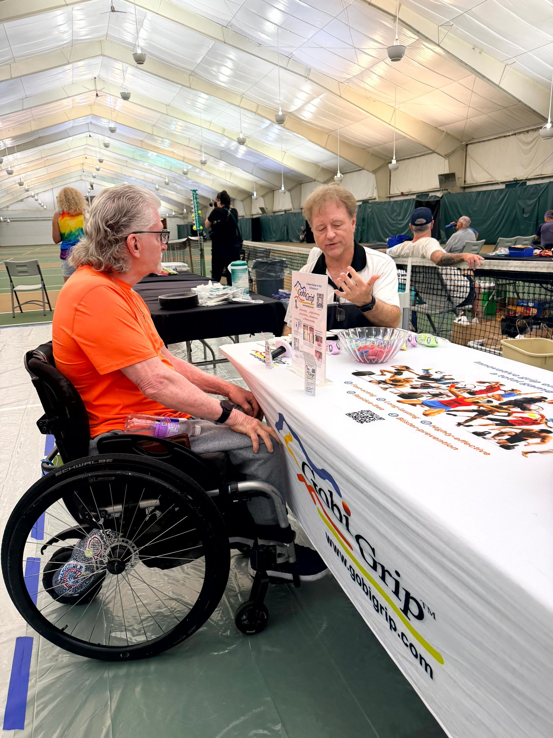 Gobi Grip inventor Dr. Mark Miller talking with a wheelchair tennis player at the Gobi Grip table at Chesterfield Athletic Club