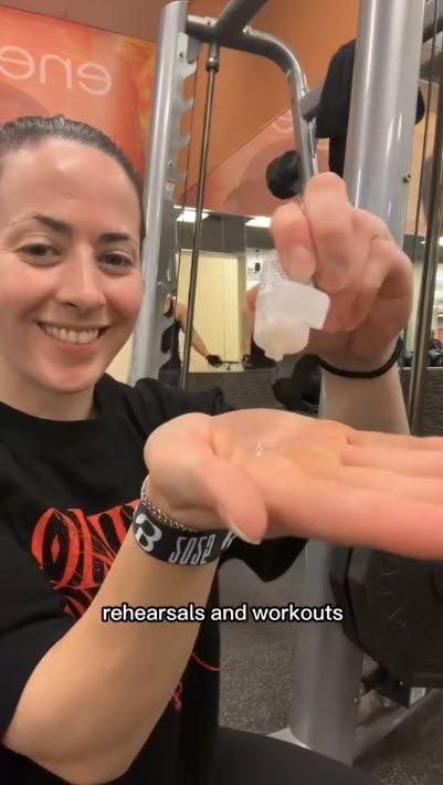 Smiling person in a gym holding a small white item over an outstretched hand