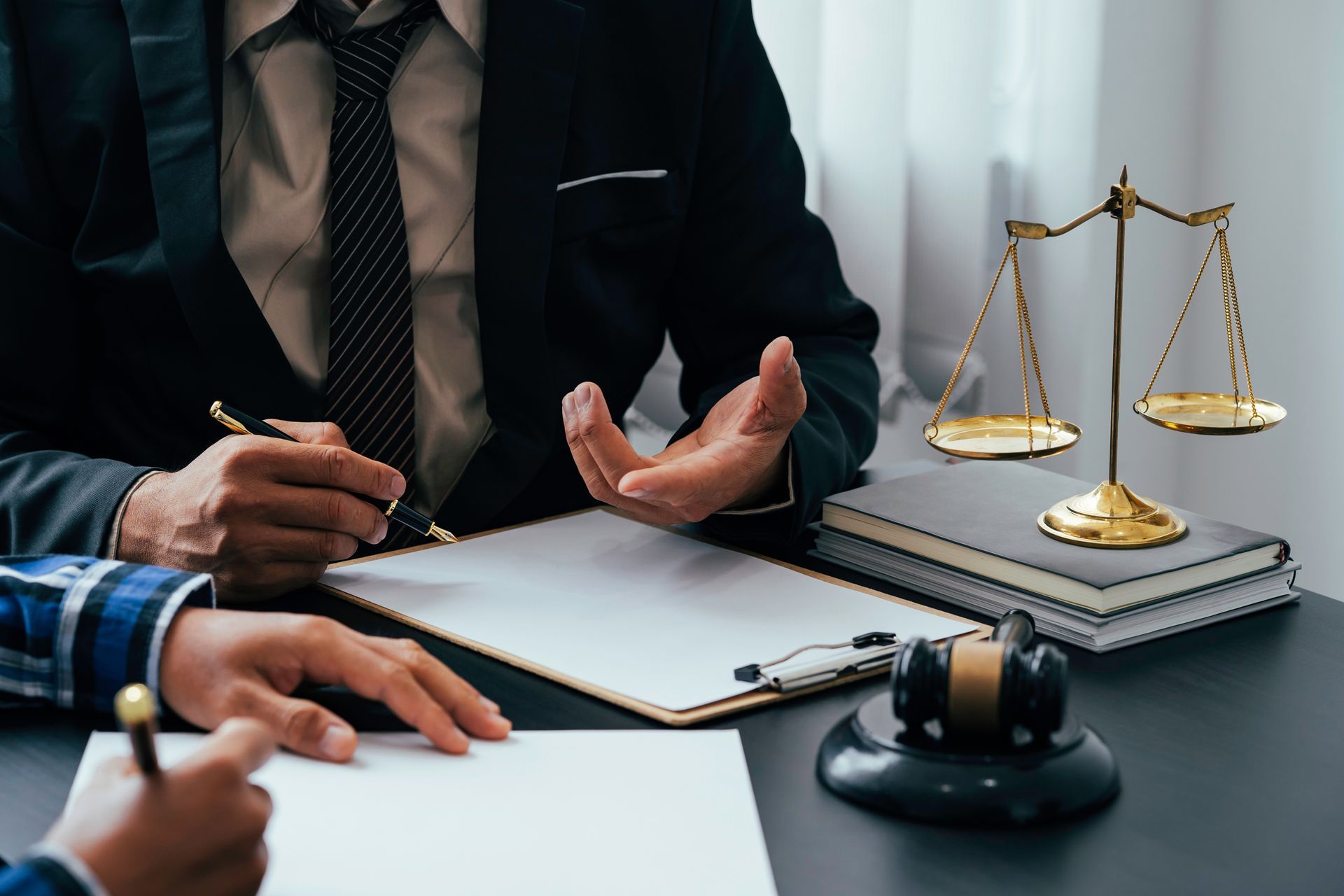 Lawyer consulting at a desk with paperwork, gavel, and scales of justice. Lawyer consulting at a desk with paperwork, gavel, and scales of justice.