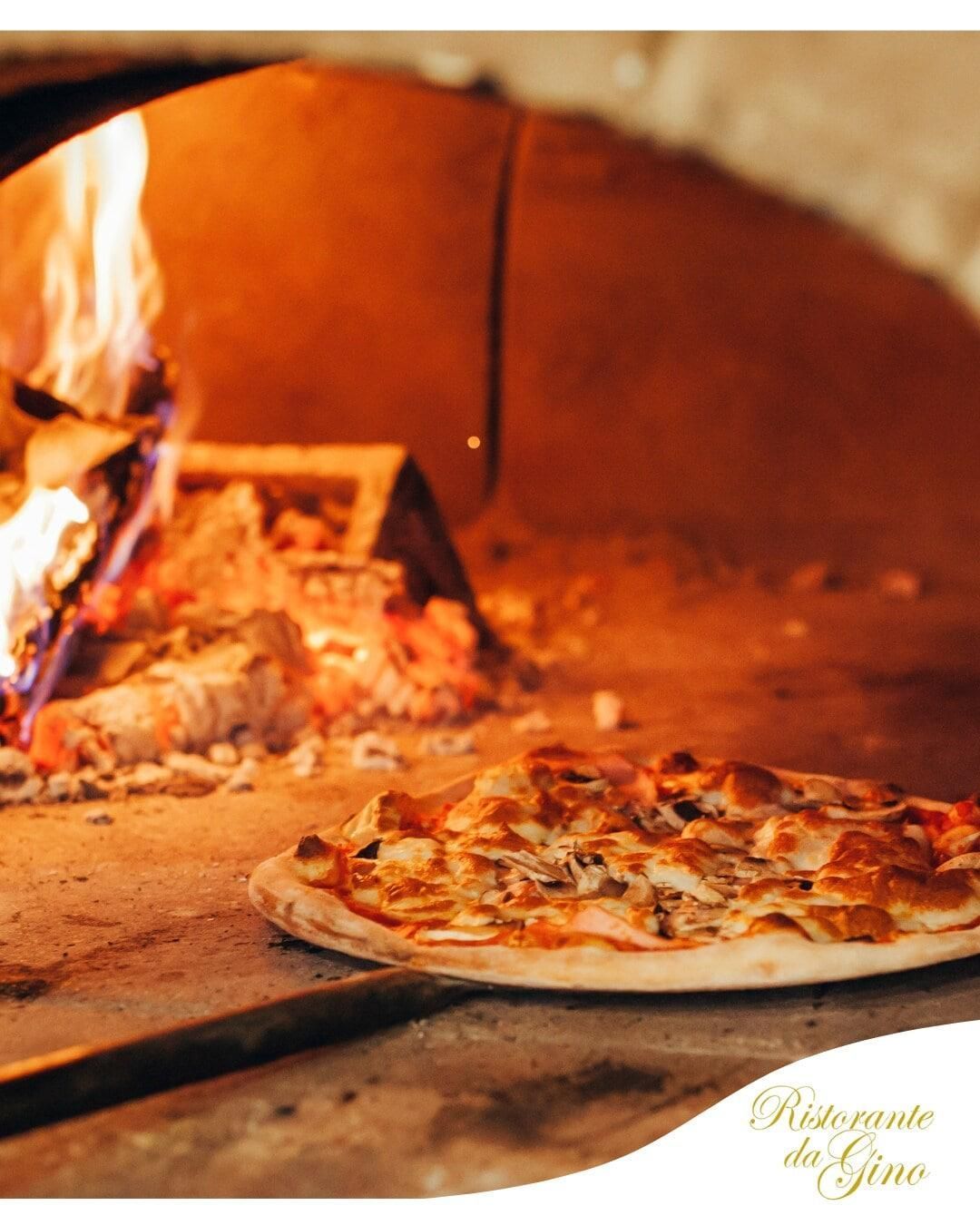 Pizza cotta in un forno a legna con fiamme e crosta dorata