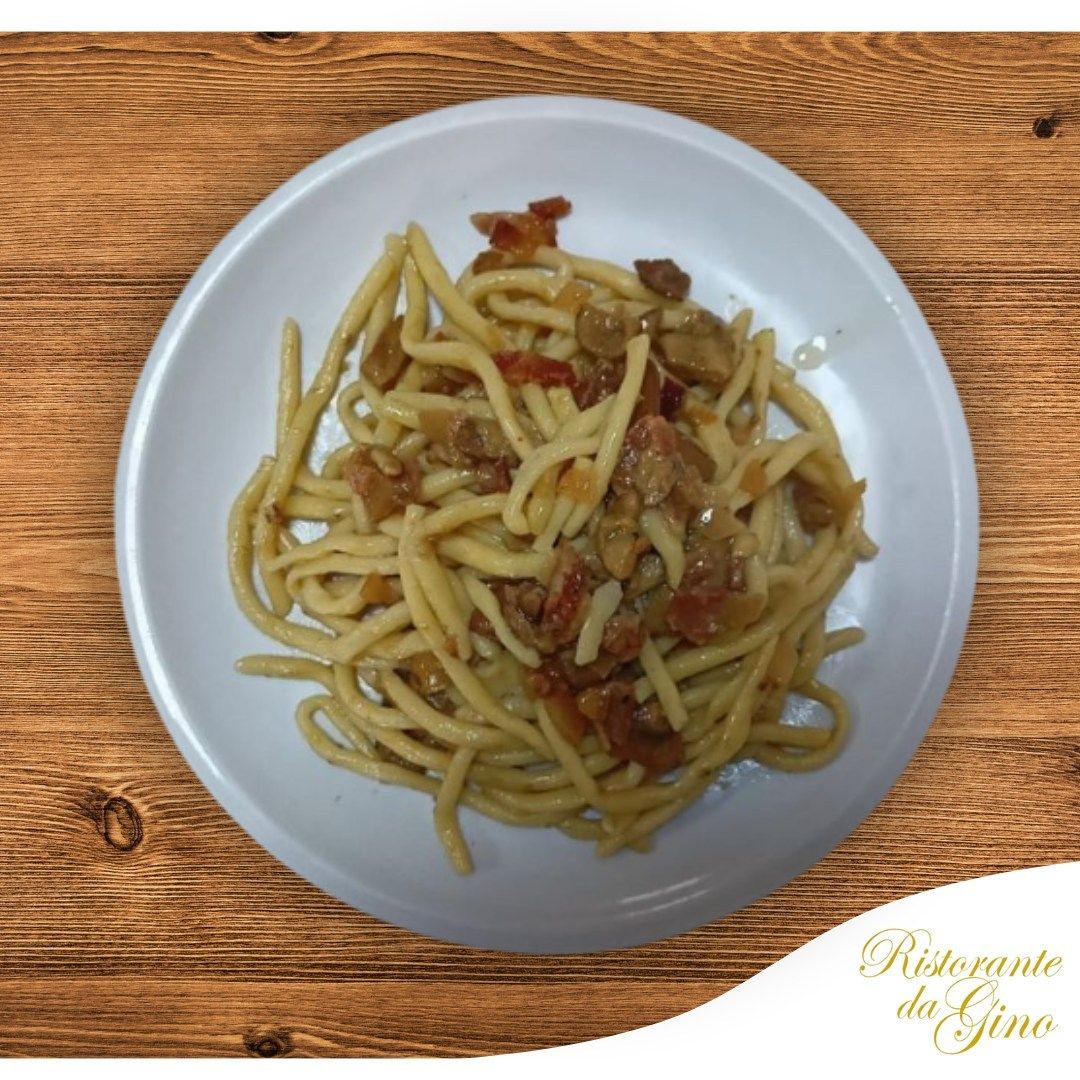 Un piatto di spaghetti semplici conditi con una piccola quantità di salsa su un tavolo di legno.