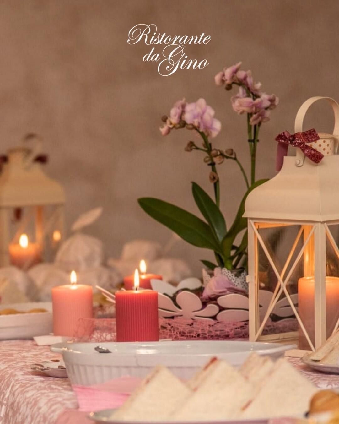 Romantico tavolo da dessert rosa con candele, fiori, lanterne e decorazioni bianche.
